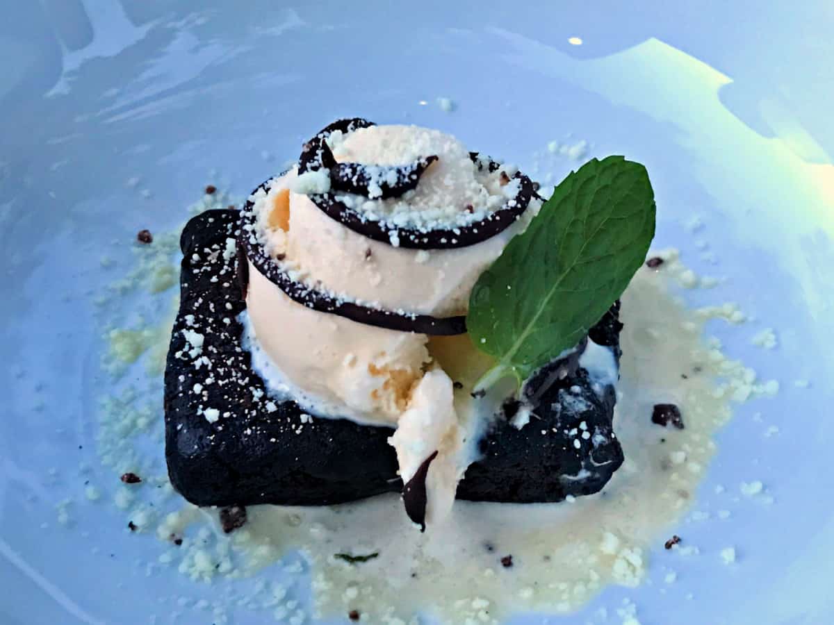 Brownie a la mode with a mint leaf.