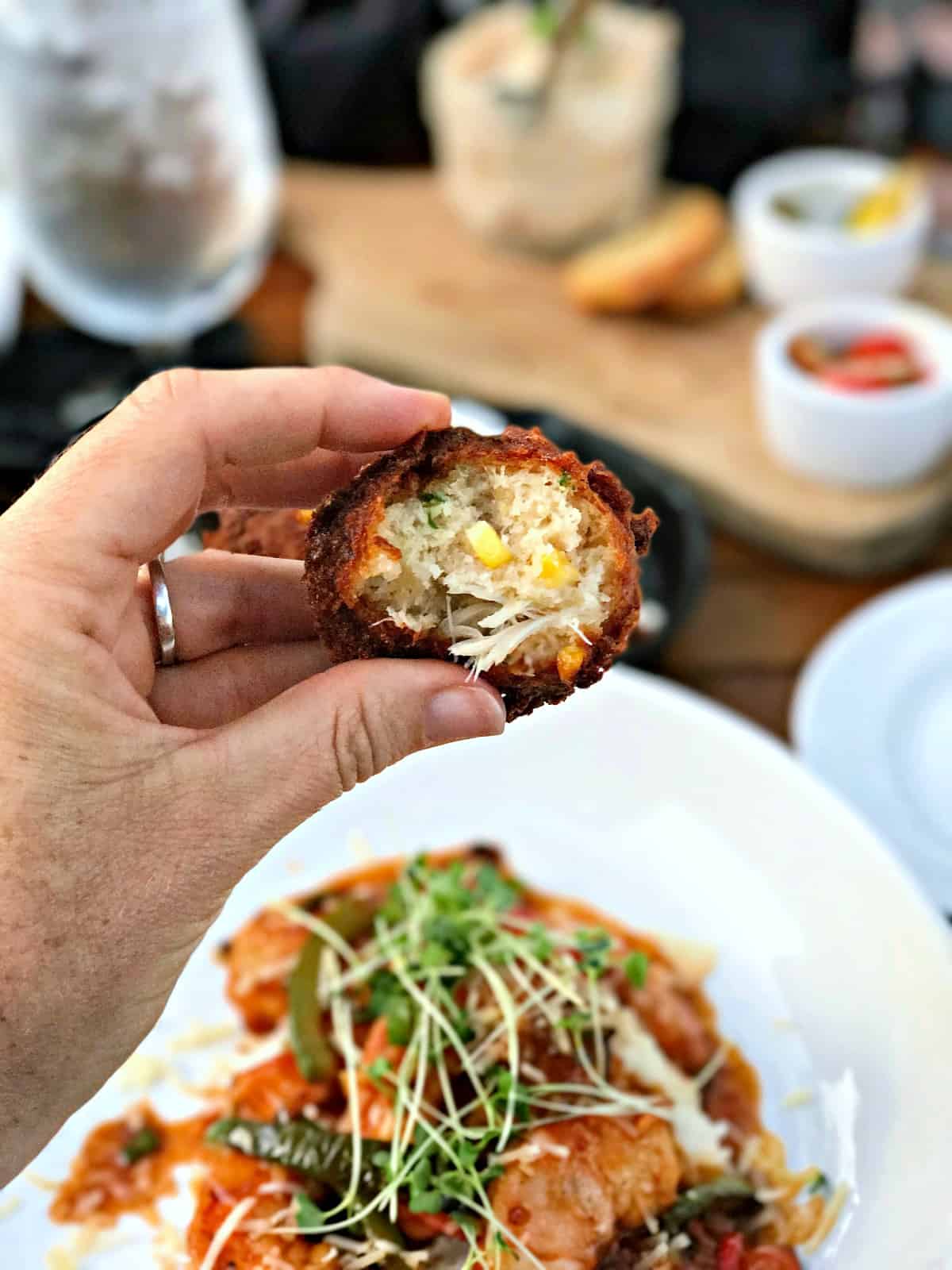 Woman holding a lump crab hush puppy.