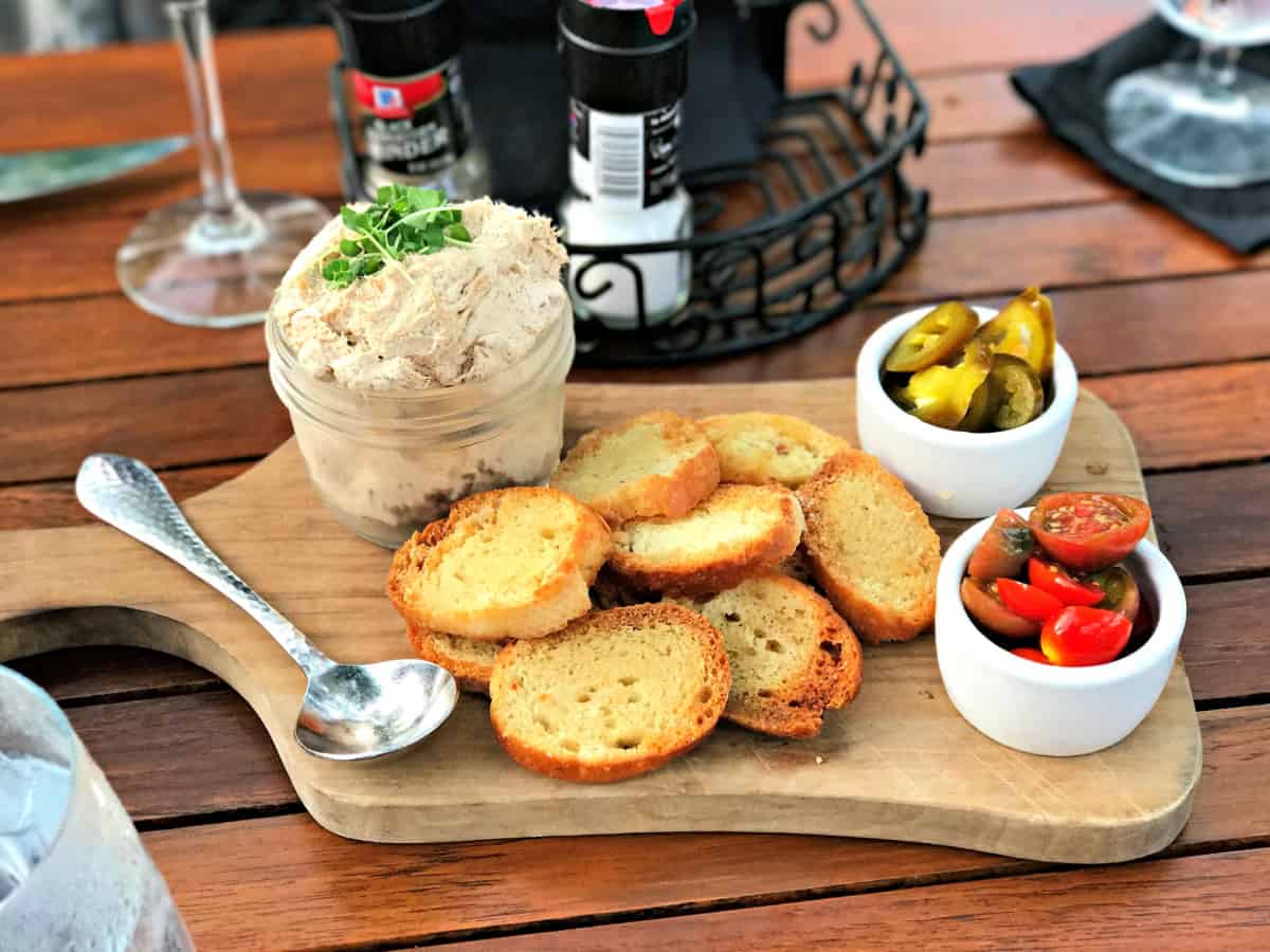 Smoked Tuna dip on a wooden board with crostini and jalapenos.