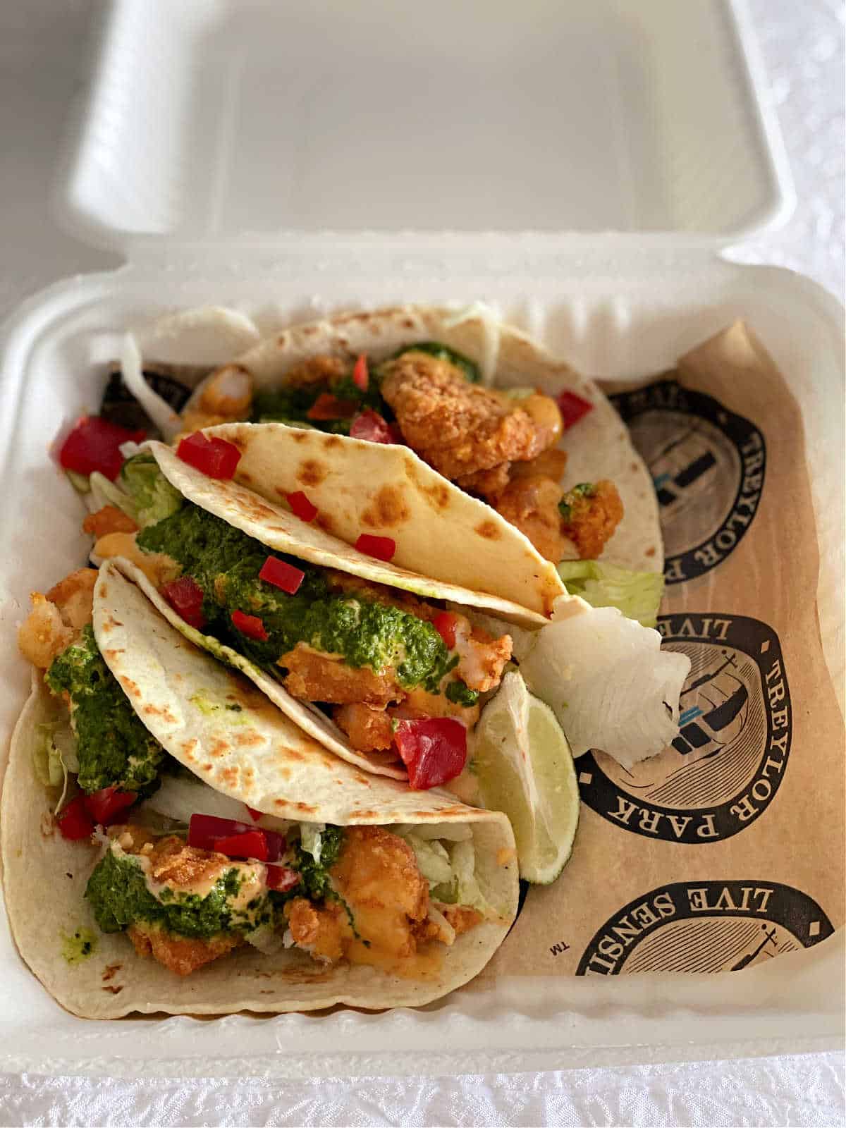 Shrimp and grits tacos topped with fresh herbs and creamy sauce on soft tortillas.