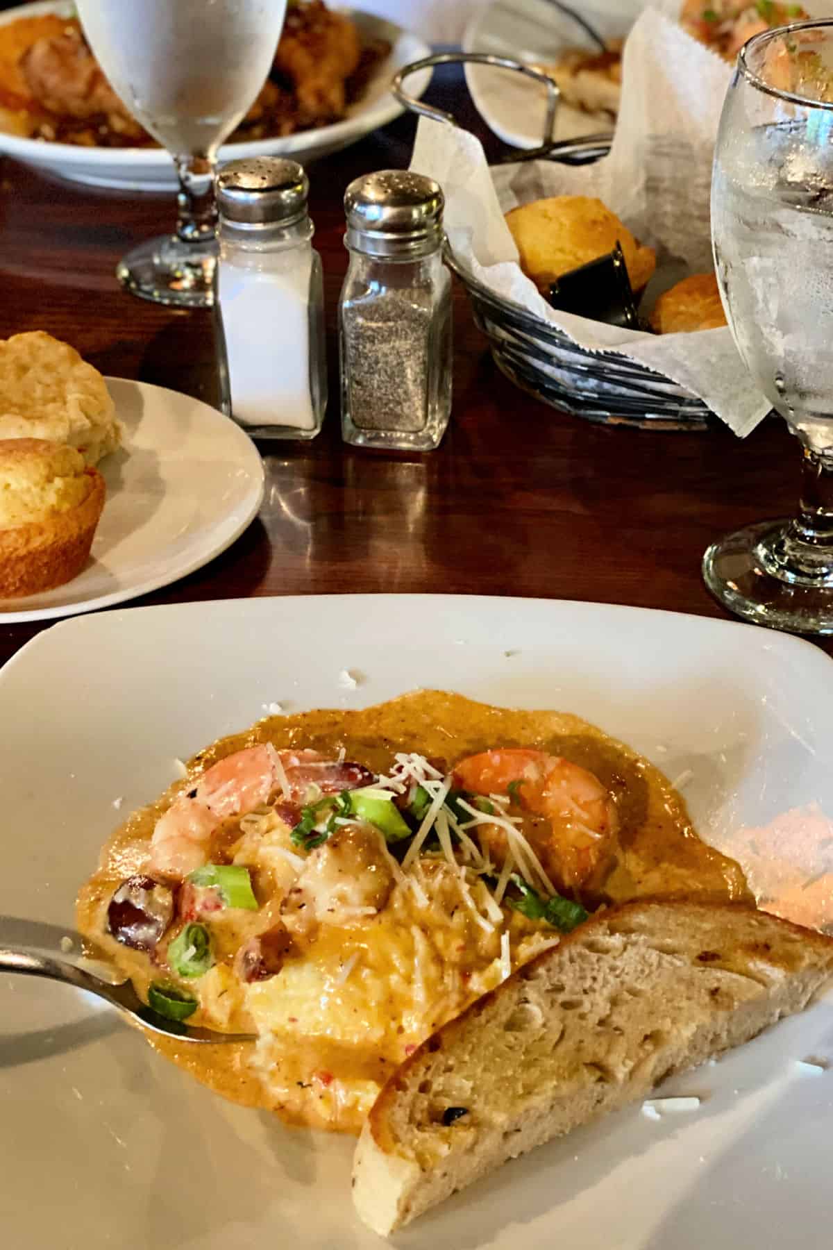 Plate of shrimp and grits with a slice of bread.