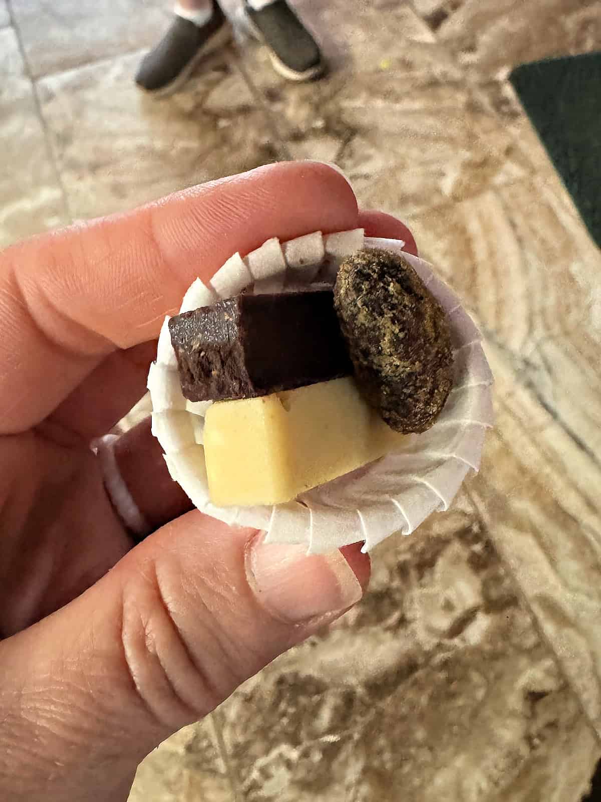 Woman holding a small sample of three types of chocolates.