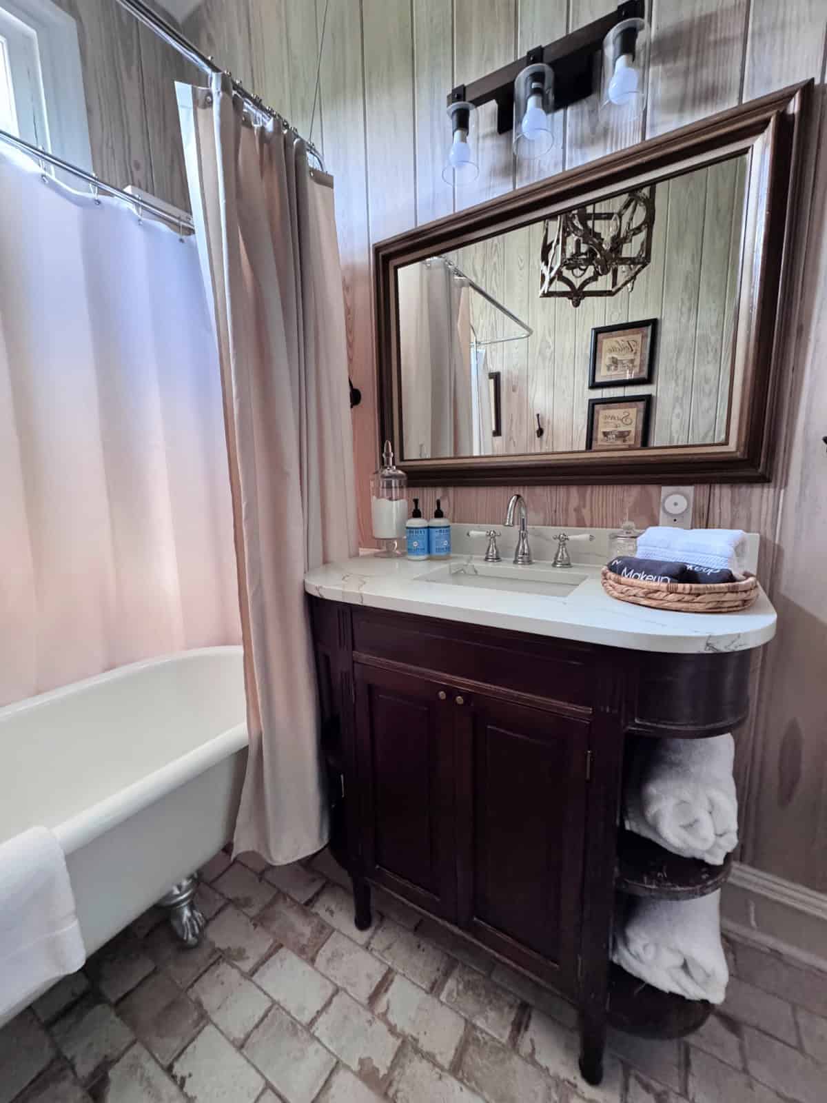 Bathroom with claw foot tub and sink with large mirror.