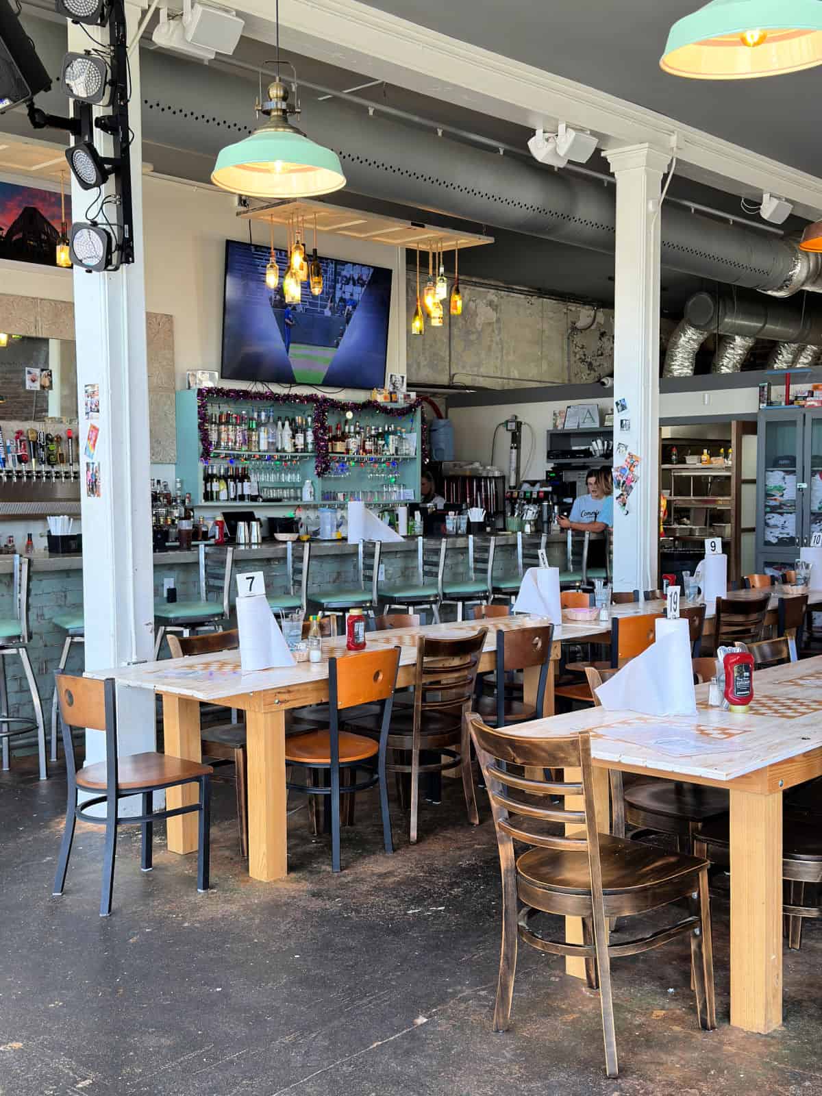 Long tables surrounded by chairs in a restaurant.