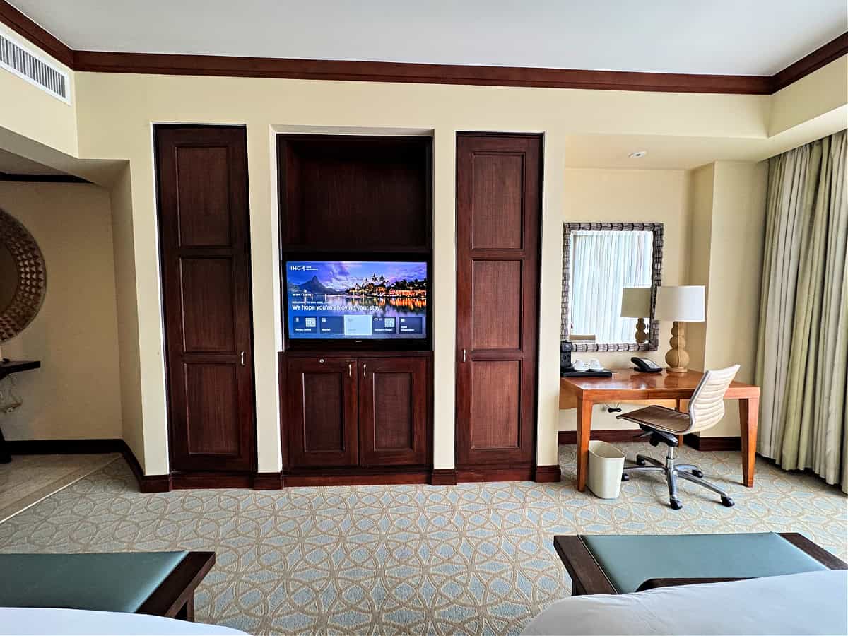 Interior view of InterContinental San Jose hotel room showing a wall-mounted TV, wooden closets, and a functional work desk area.