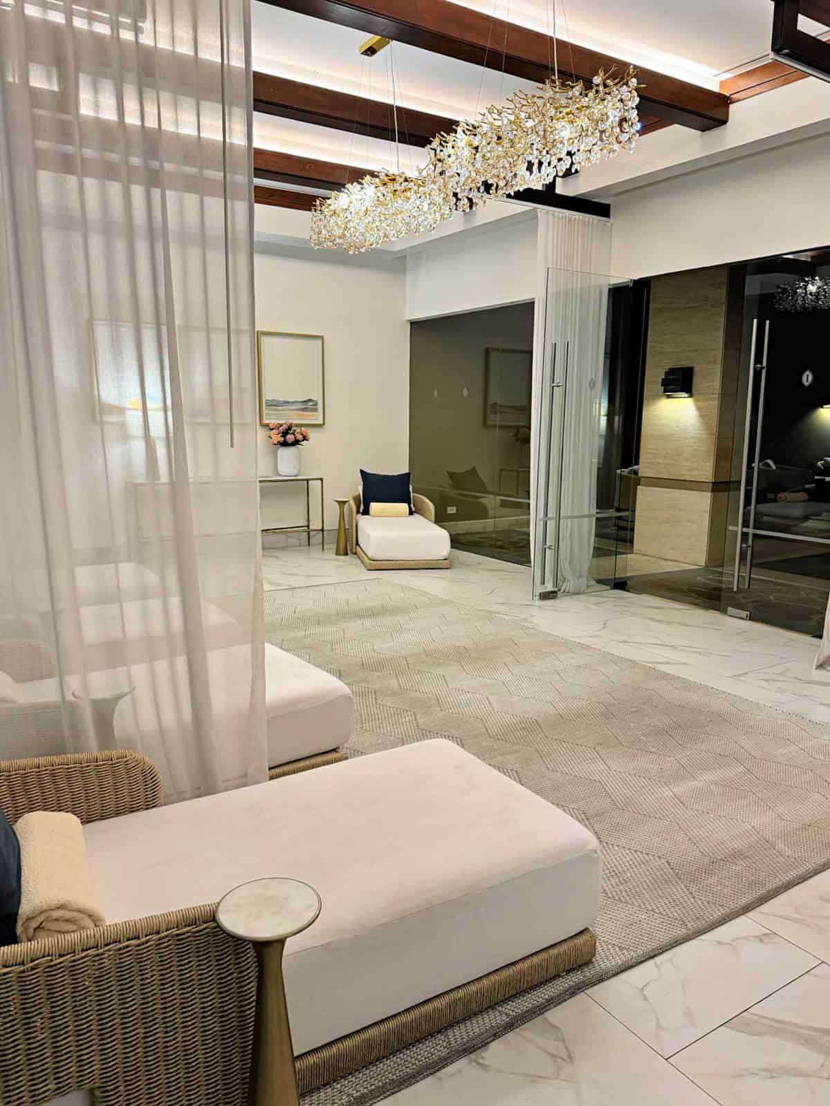 Tranquil spa lounge at Presence Spa & Wellness Center with soft seating and an elegant modern chandelier light fixture hanging above.
