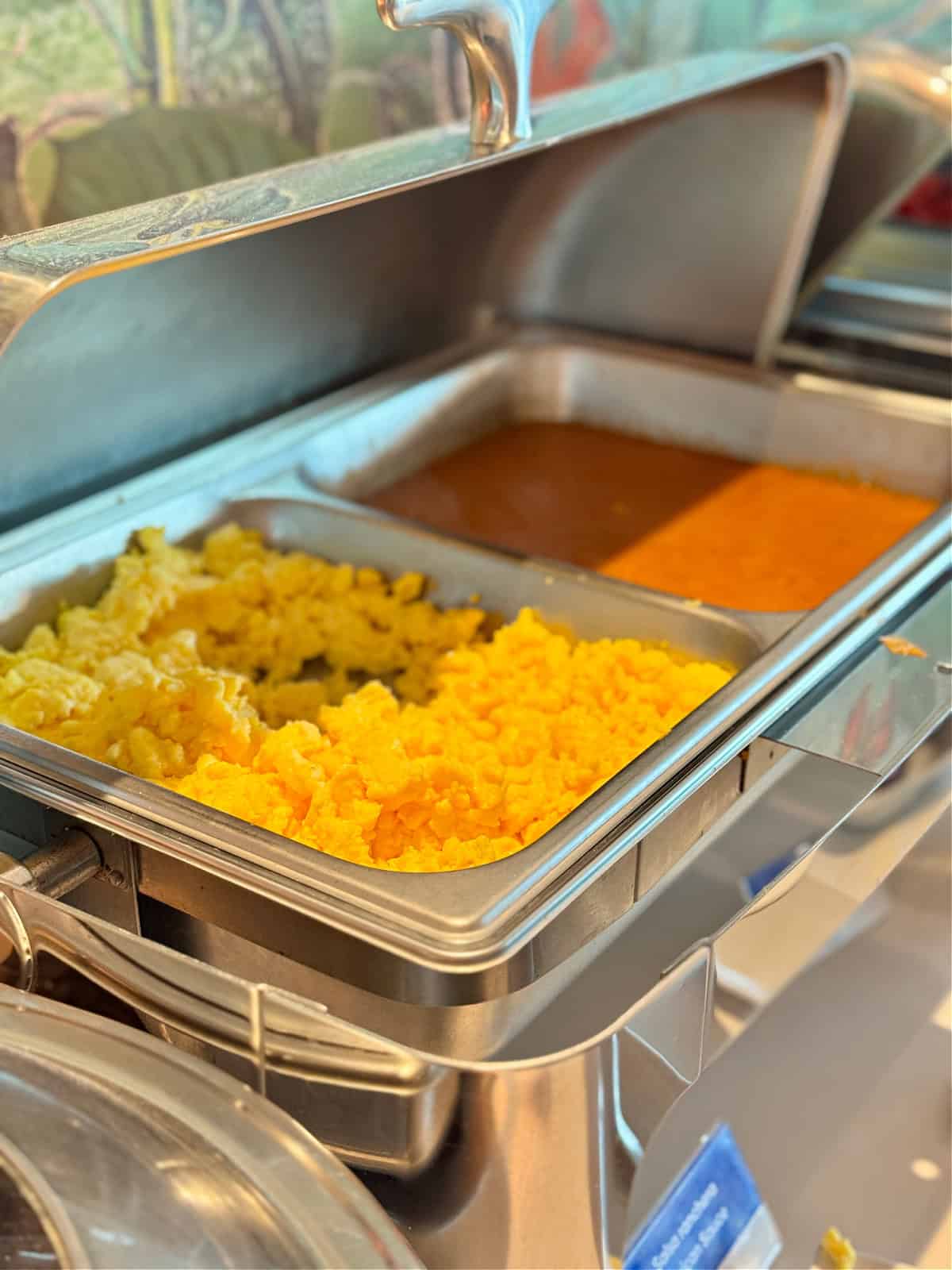 Scrambled eggs in a chaffing dish next to a Mexican salsa.