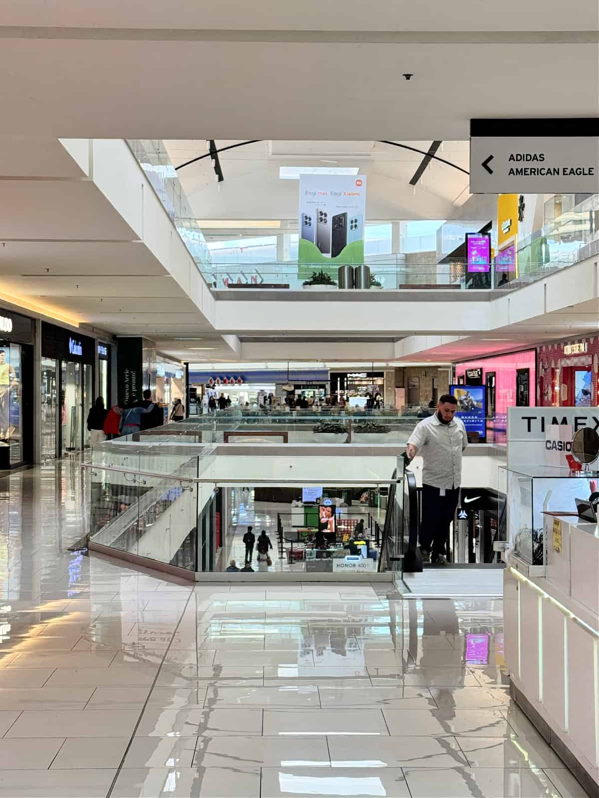 Interior view of Multiplaza Mall in San José, Costa Rica, showcasing three levels of sleek, modern shops with sparkling clean floors and bright lighting.