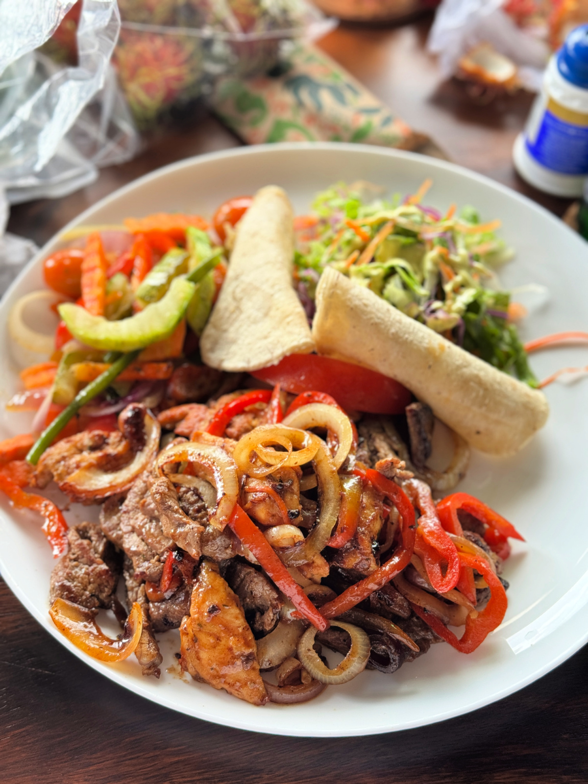 A plate of Costa Rican fajitas with sautéed peppers, onions, beef, and chicken served with fresh salad and tortillas.
