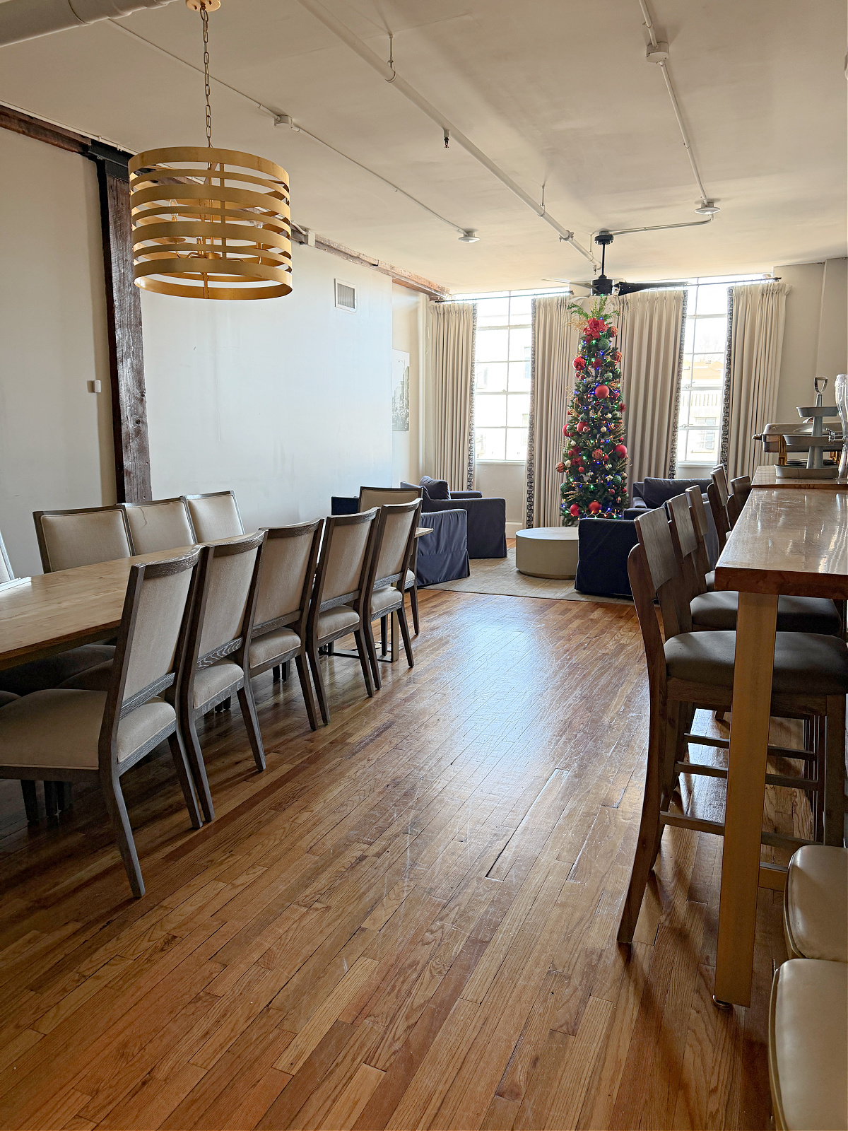 The Belk Hudson Room at The Stricklin Hotel in Florence, Alabama, featuring a long conference table, upholstered chairs, blue cabinetry, coffee station, and modern lighting.