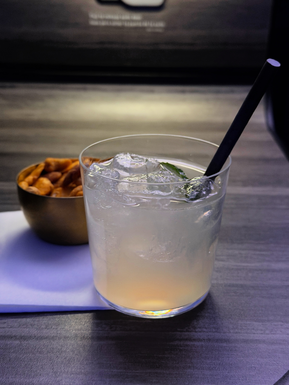 JetBlue Mint welcome cocktail served over ice with a bowl of snack mix on the side in a private suite.