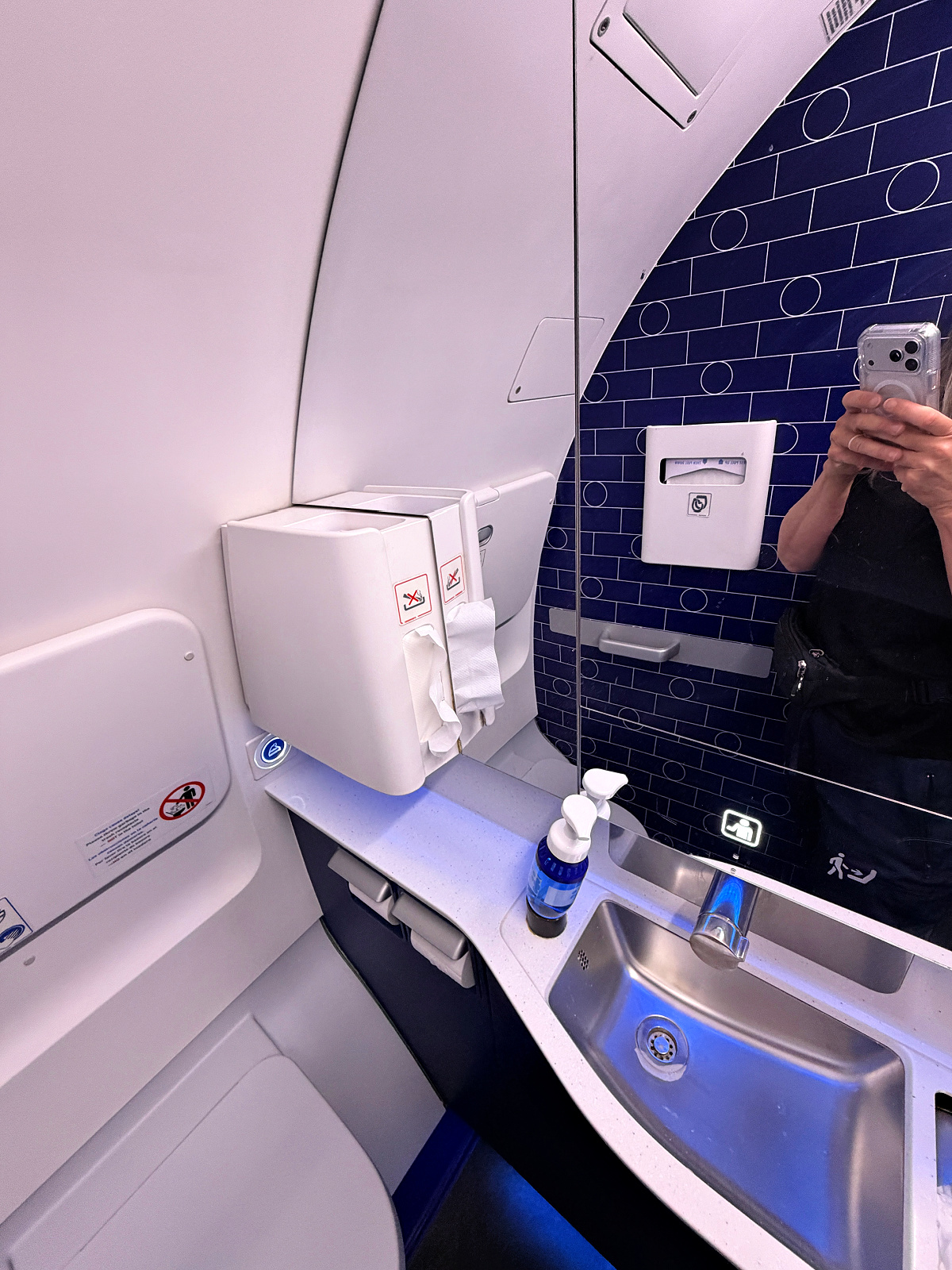 JetBlue Mint aircraft lavatory with sink, mirror, soap dispenser, and modern blue accent wall.
