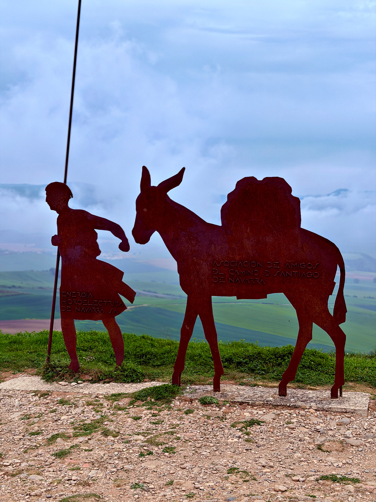 Metal sculpture of a pilgrim and pack mule overlooking the countryside near Alto del Perdón on the Camino de Santiago.