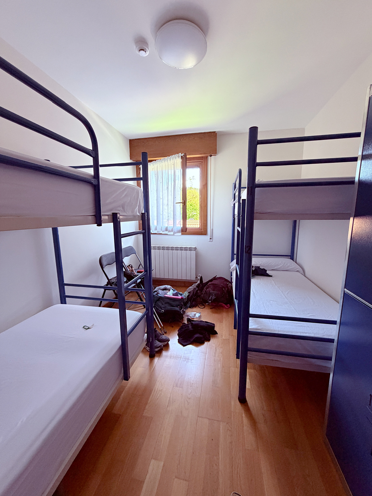 Shared albergue room on the Camino de Santiago with four bunk beds, pilgrim backpacks, and simple accommodations for overnight stays.