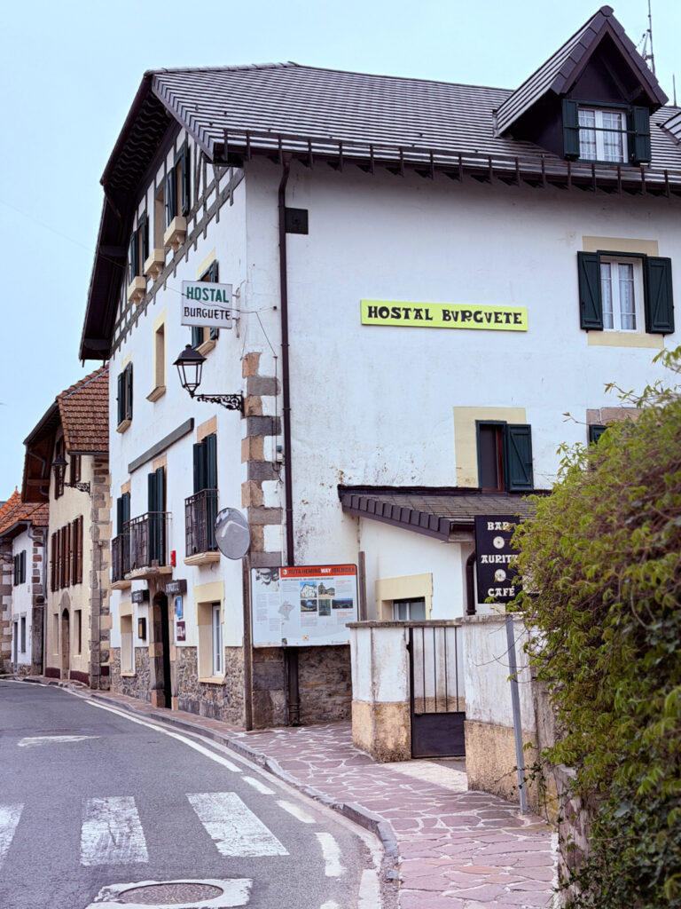 Exterior view of Hostal Burguete, a traditional white building along a quiet street in Burguete, Spain.