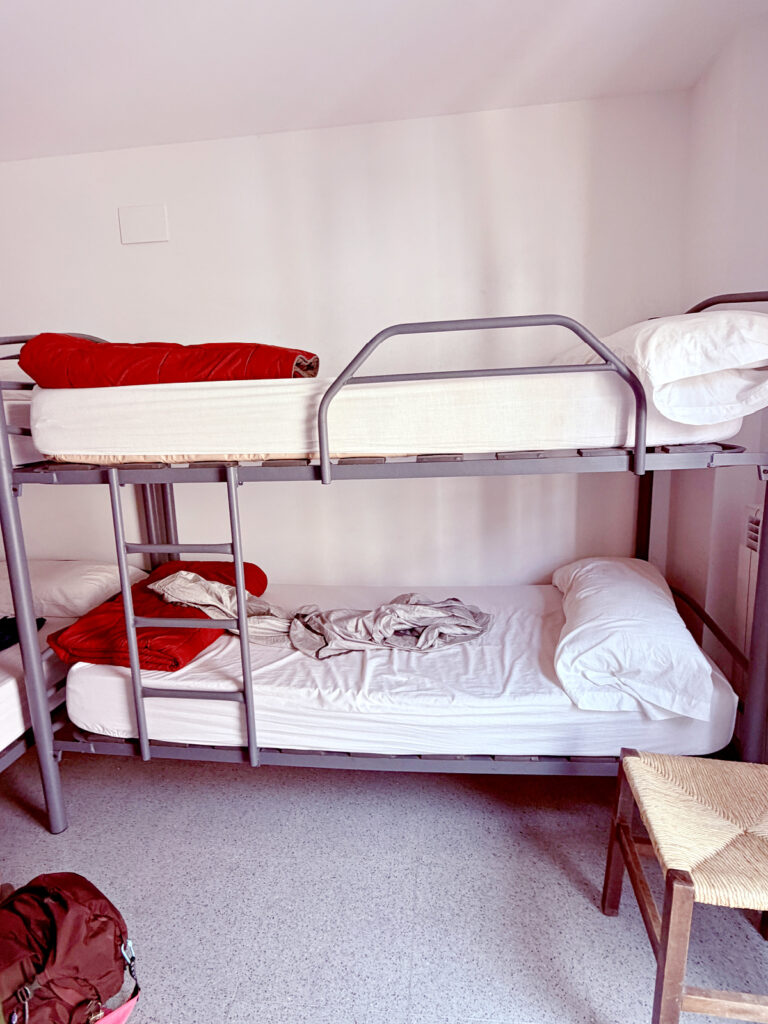 Shared room at Izar Hostel in Zubiri featuring several bunk beds topped with red quilts.