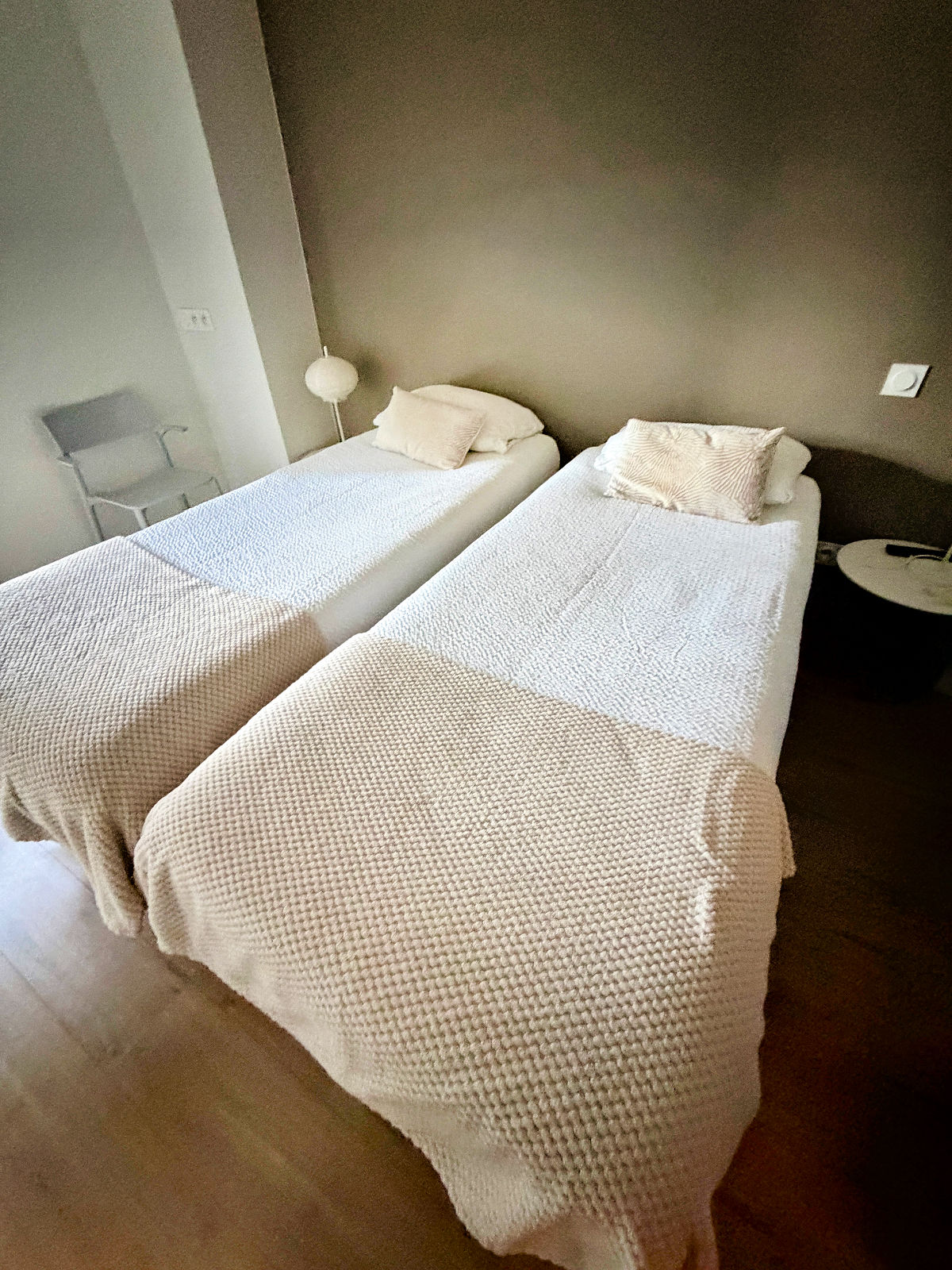 Private twin room on the Camino de Santiago featuring two single beds with textured white bedspreads and modern décor.