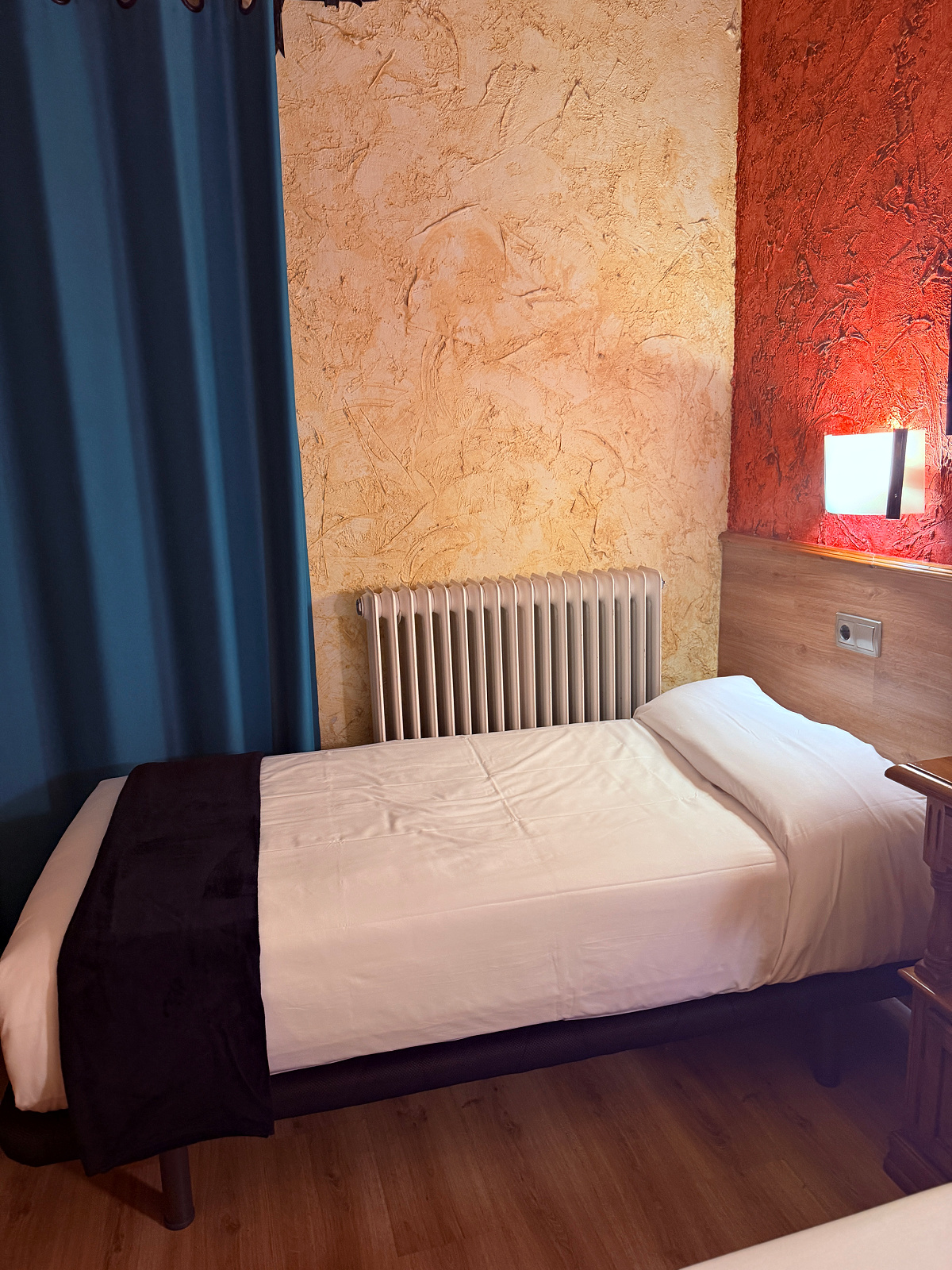 Cozy room with two twin beds, colorful accent walls, and a comfortable bed in Puente la Reina, Spain.