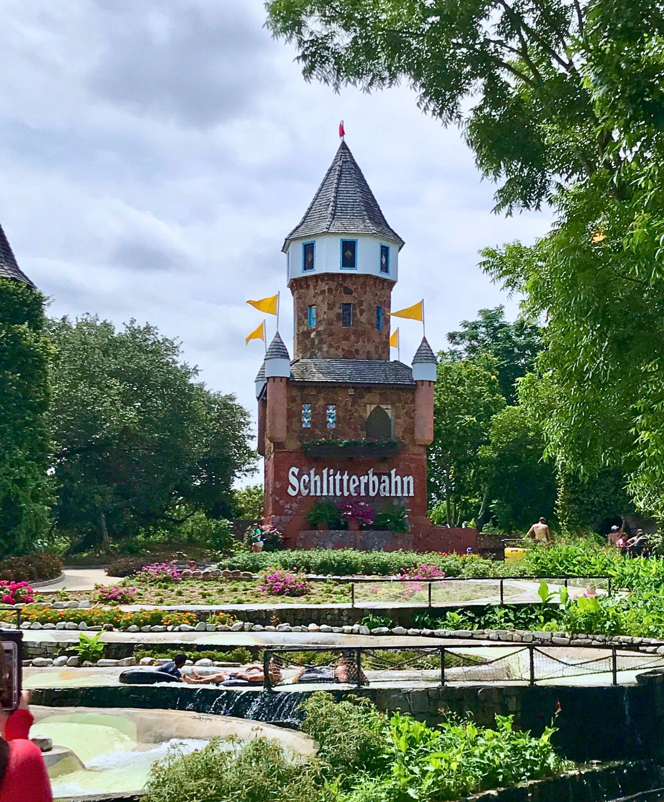 Schlitterbahn - The World's Best Water Park Schlitterbahn New Braunfels castle-style tower surrounded by colorful flowers, lush landscaping, and water attractions on a sunny Texas day.