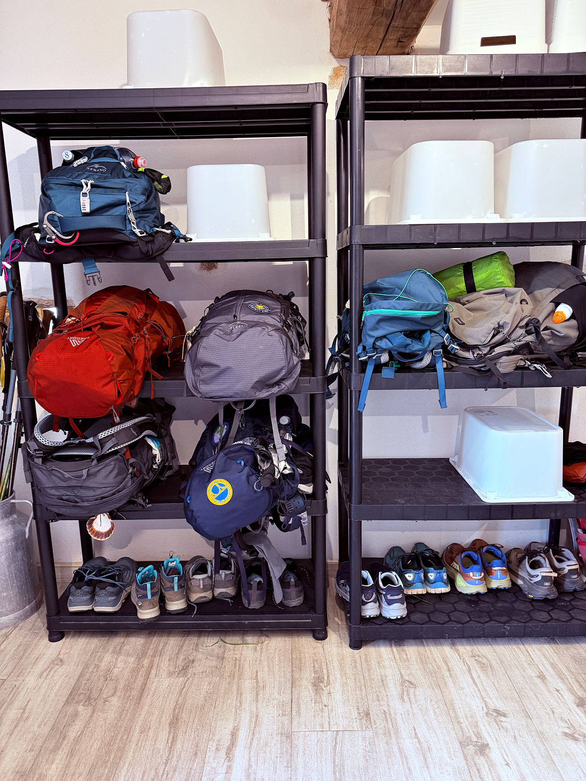 Pilgrim backpacks and hiking shoes stored on shelves inside Auberge Borda along the Camino de Santiago.