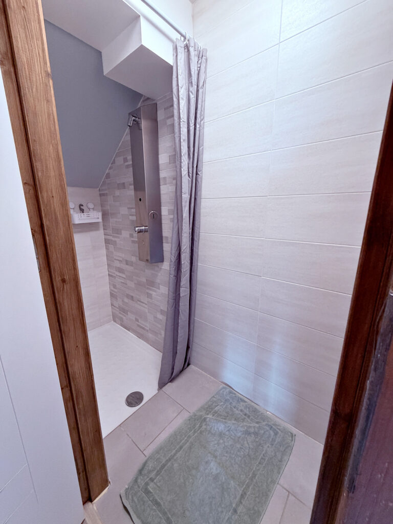Modern shared shower with walk-in design for Camino pilgrims staying at Auberge Borda.