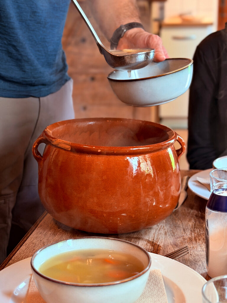 Hot soup being served from a large rustic pot during dinner at Auberge Borda.