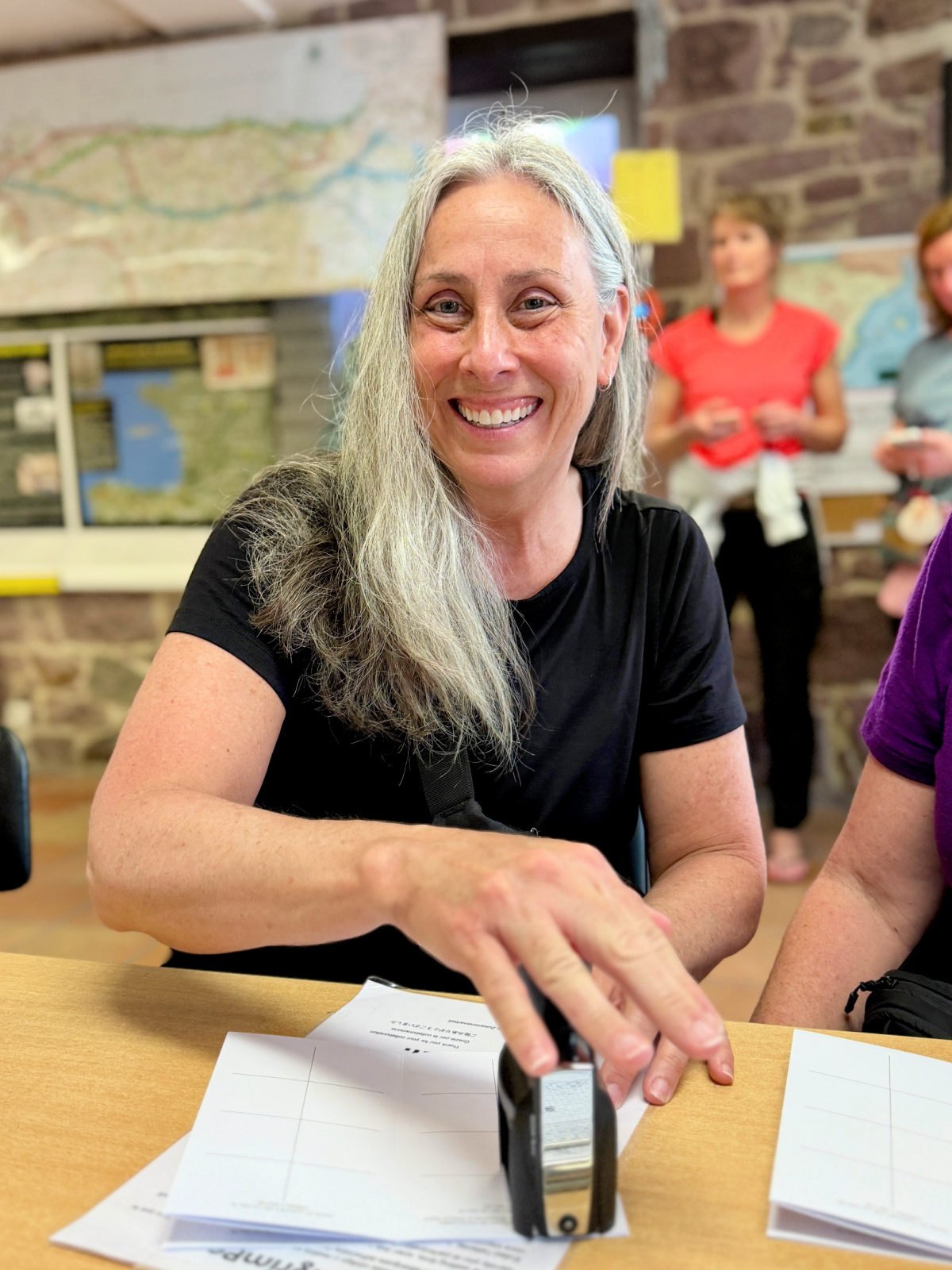 Smiling Camino pilgrim stamping her Camino passport at the Pilgrim's Office in Saint-Jean-Pied-de-Port before beginning the Camino de Santiago.