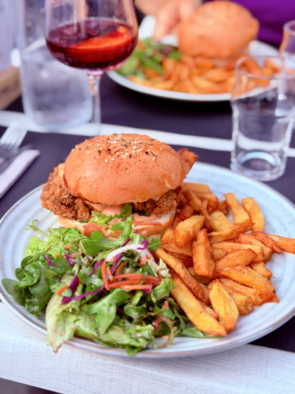 Crispy chicken sandwich served with hand-cut French fries and a fresh side salad at a restaurant near Hotel La Villa Esponda in Saint-Jean-Pied-de-Port.