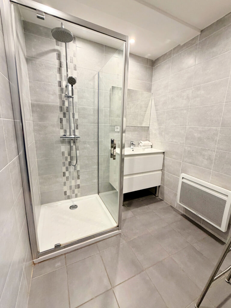 Modern bathroom at Hotel La Villa Esponda featuring a walk-in glass shower, vanity, and fresh towels.