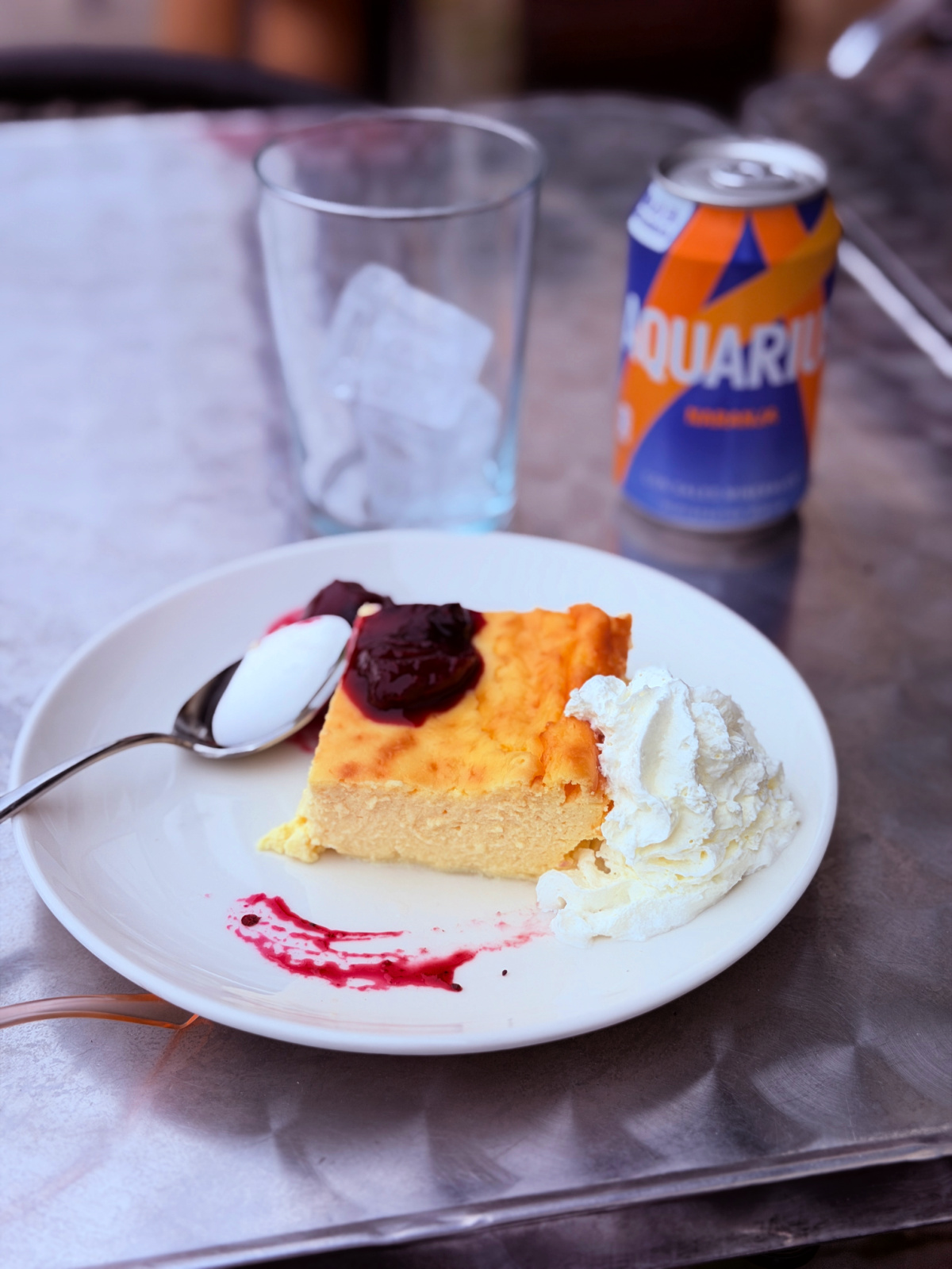Basque cheesecake with berry sauce and whipped cream served with an Aquarius drink in Roncesvalles, Spain.