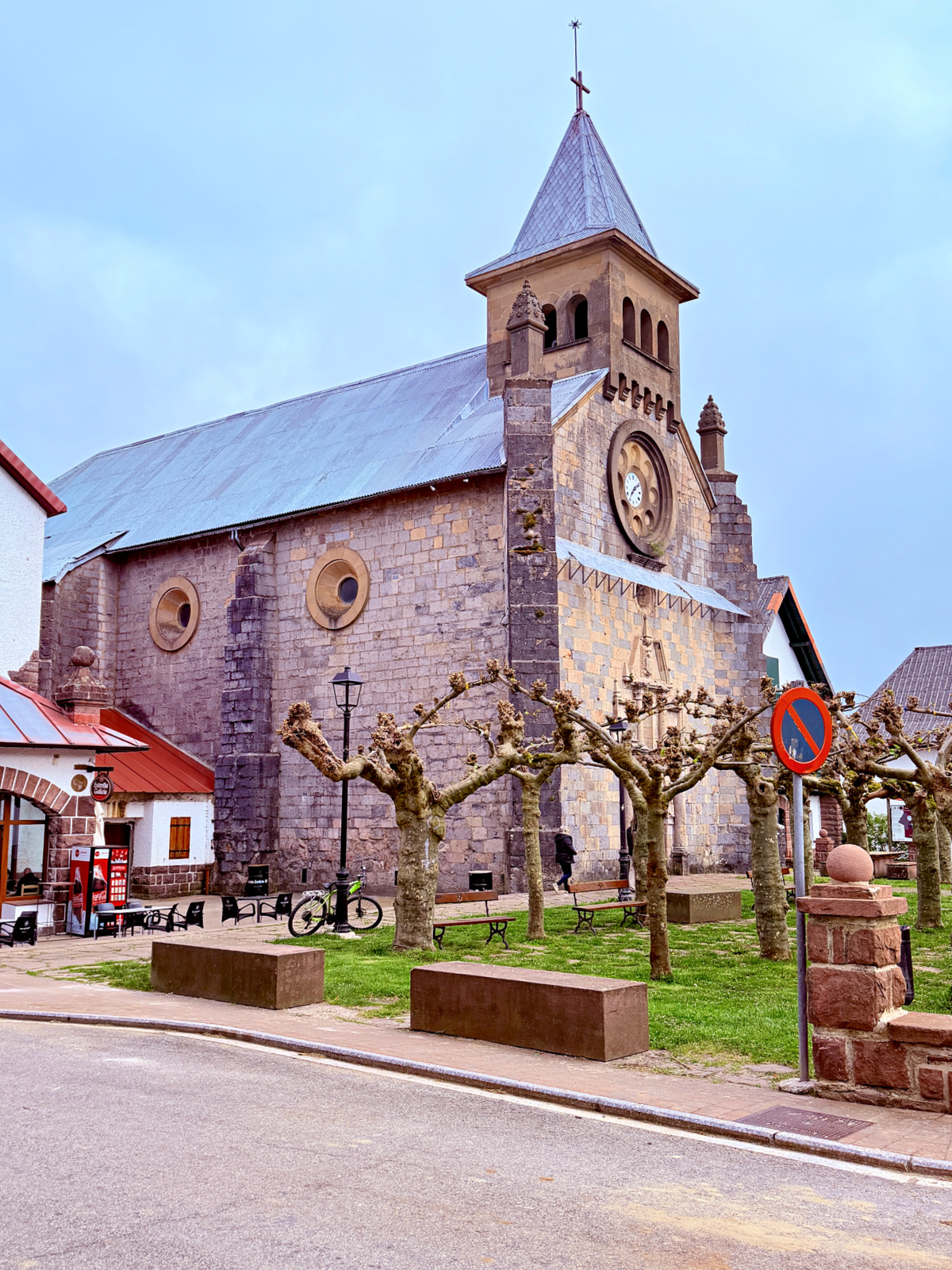 Stone church with bell tower and pruned trees in the village of Burguete, Spain.
