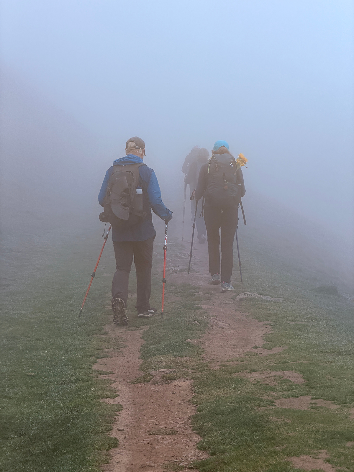 Pilgrims hiking through dense fog on the Napoleon Route across the Pyrenees.