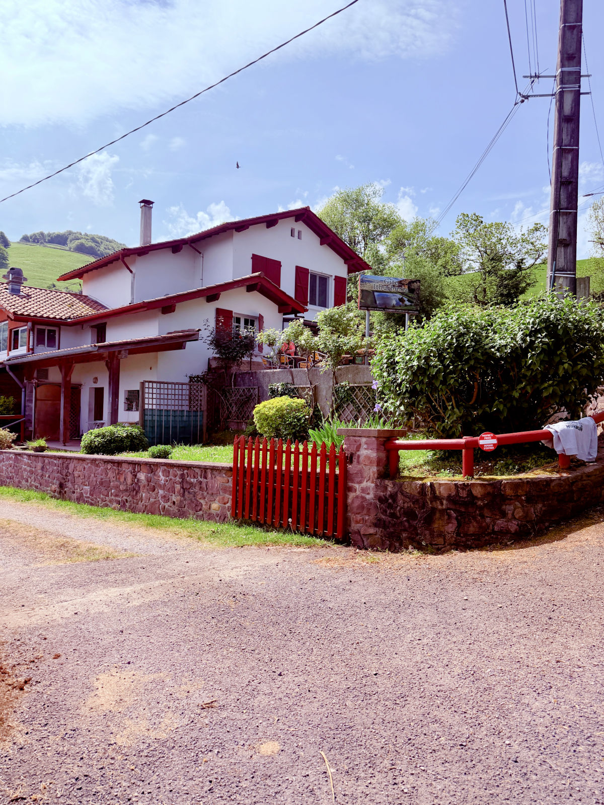 Gîte Ithurburia with white walls, red shutters, and a red gate along the Camino route in the French Basque Country.