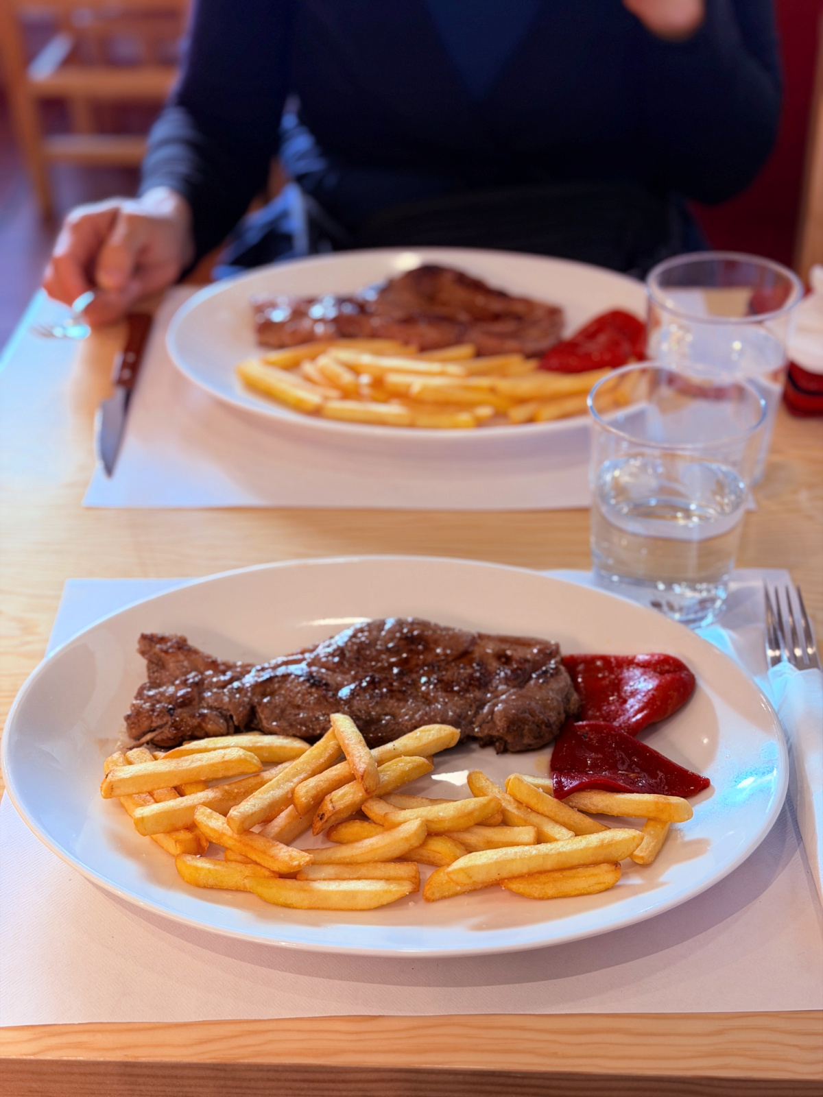 Steak with French fries and roasted red peppers served for dinner in Burguete, Spain.