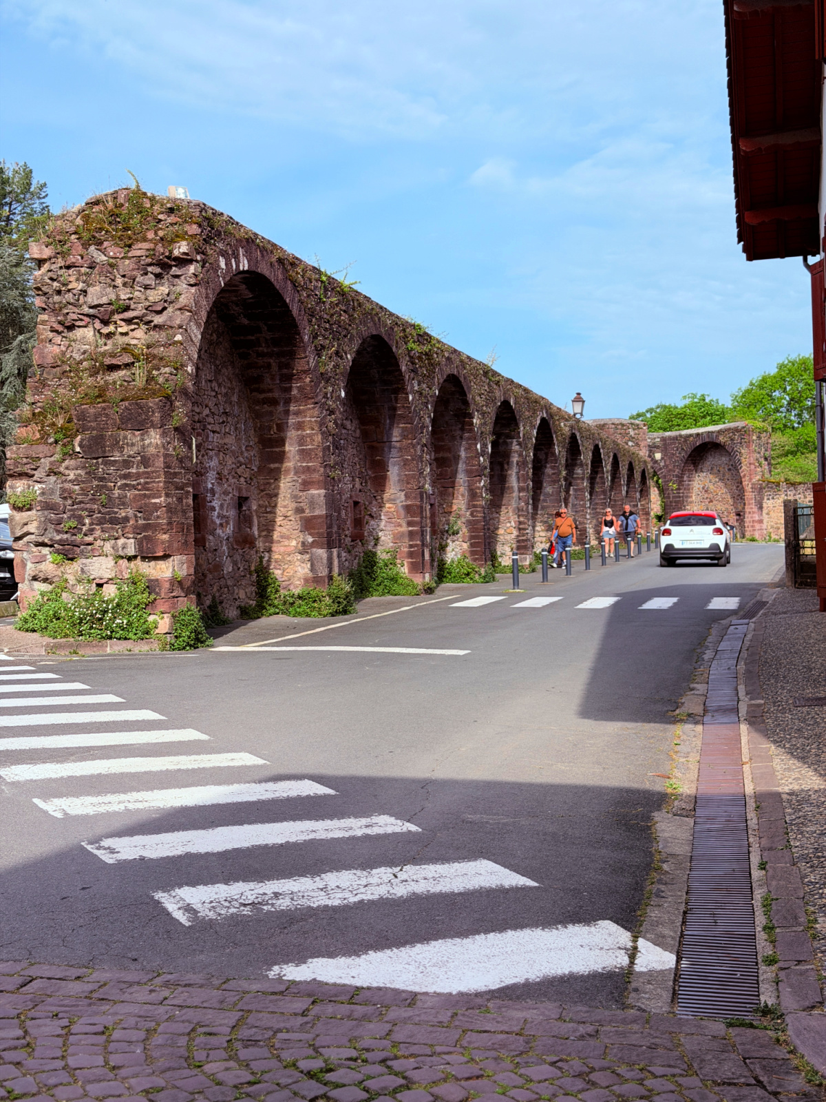 Historic stone arches running alongside a street in Saint-Jean-Pied-de-Port, France.