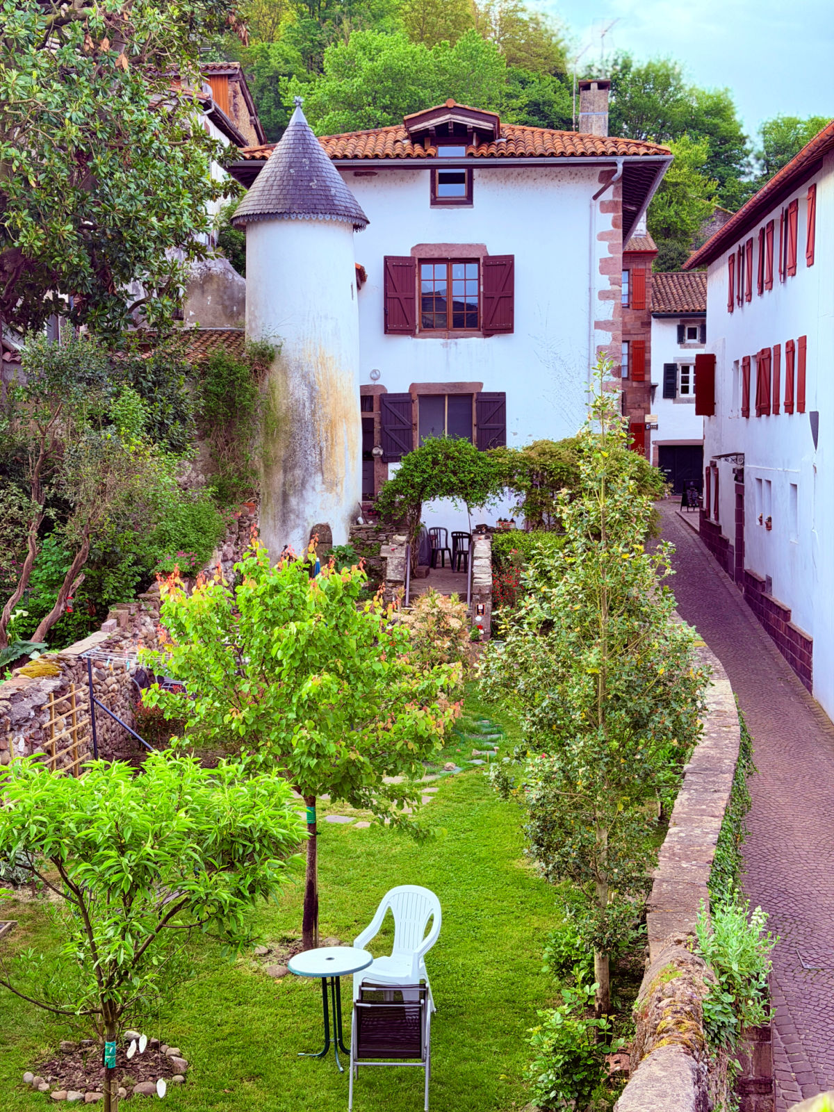 Quiet garden surrounded by traditional white Basque houses with red shutters in Saint-Jean-Pied-de-Port.