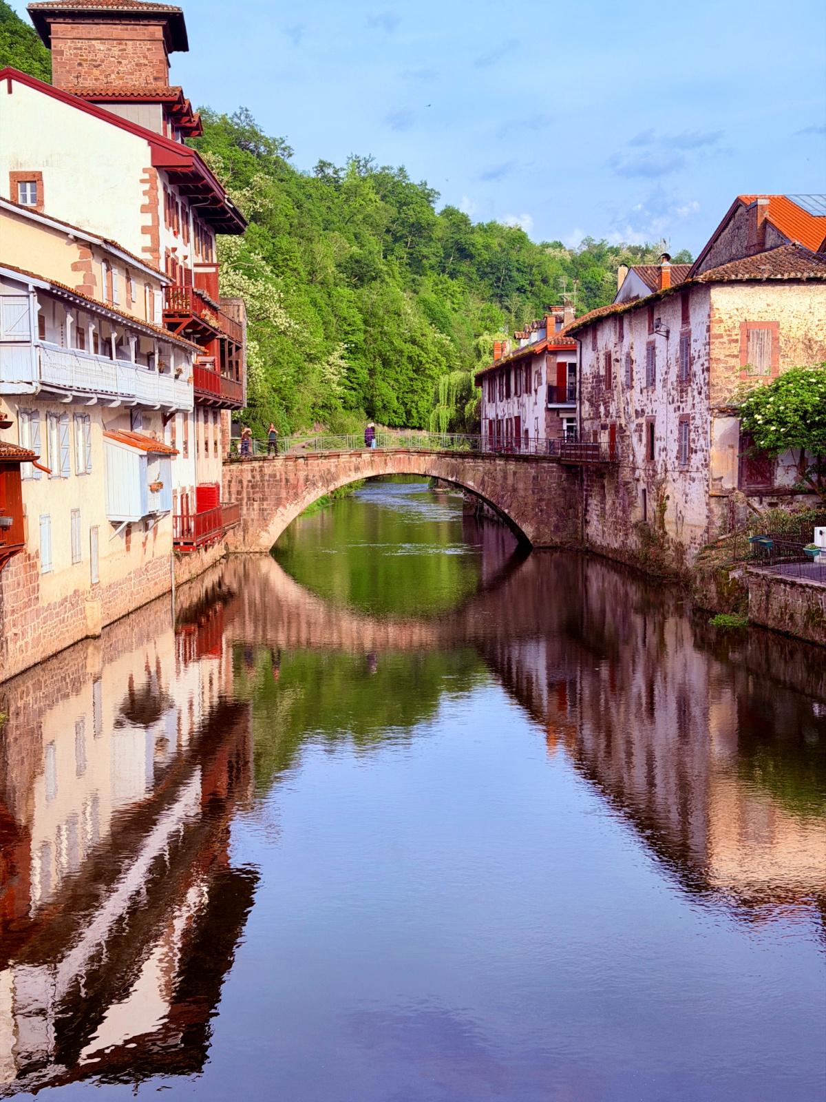 Stone bridge crossing the Nive River between traditional buildings in Saint-Jean-Pied-de-Port, France.