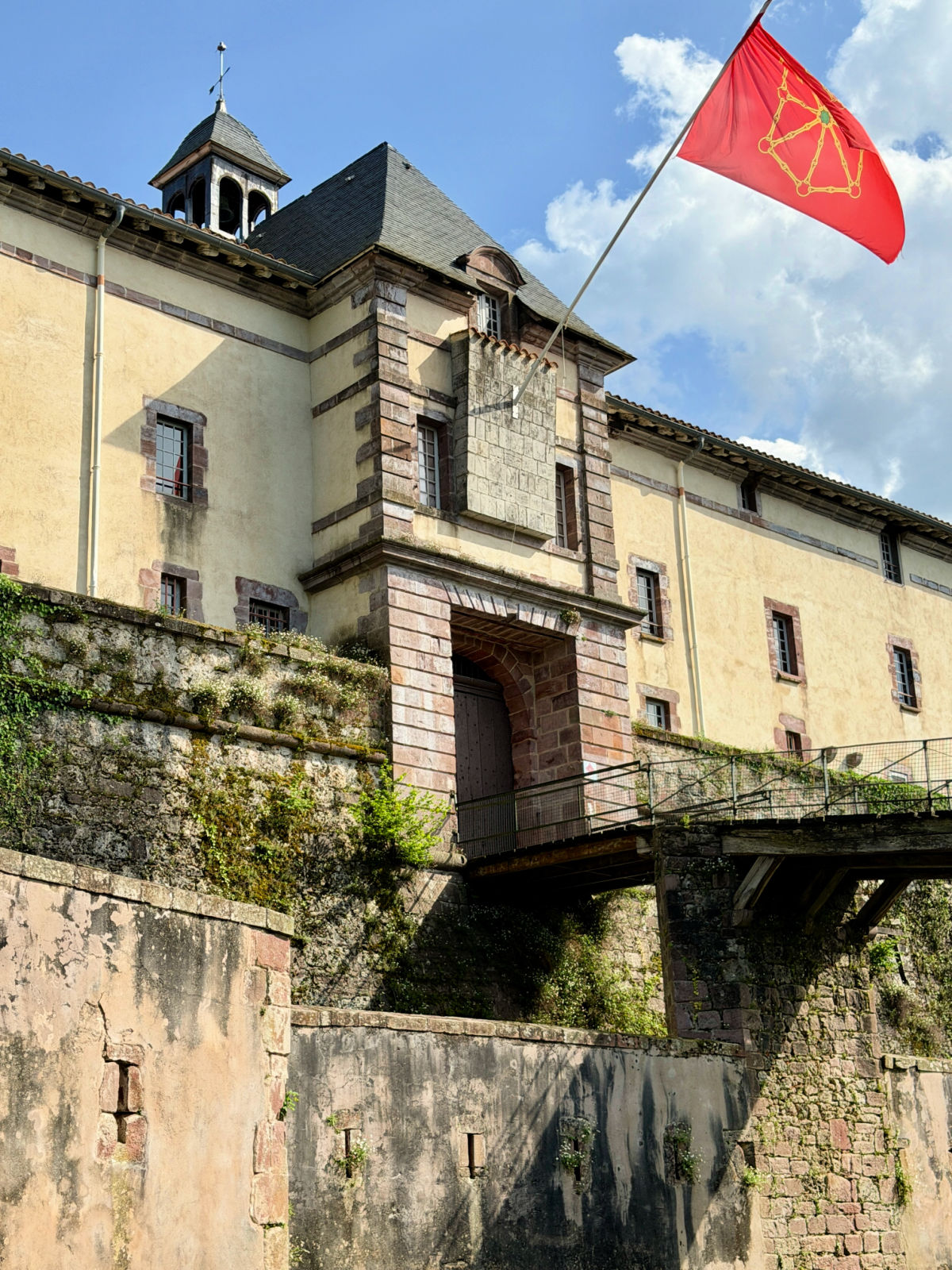 Historic citadel above Saint-Jean-Pied-de-Port with the red flag of Navarre flying against a blue sky.