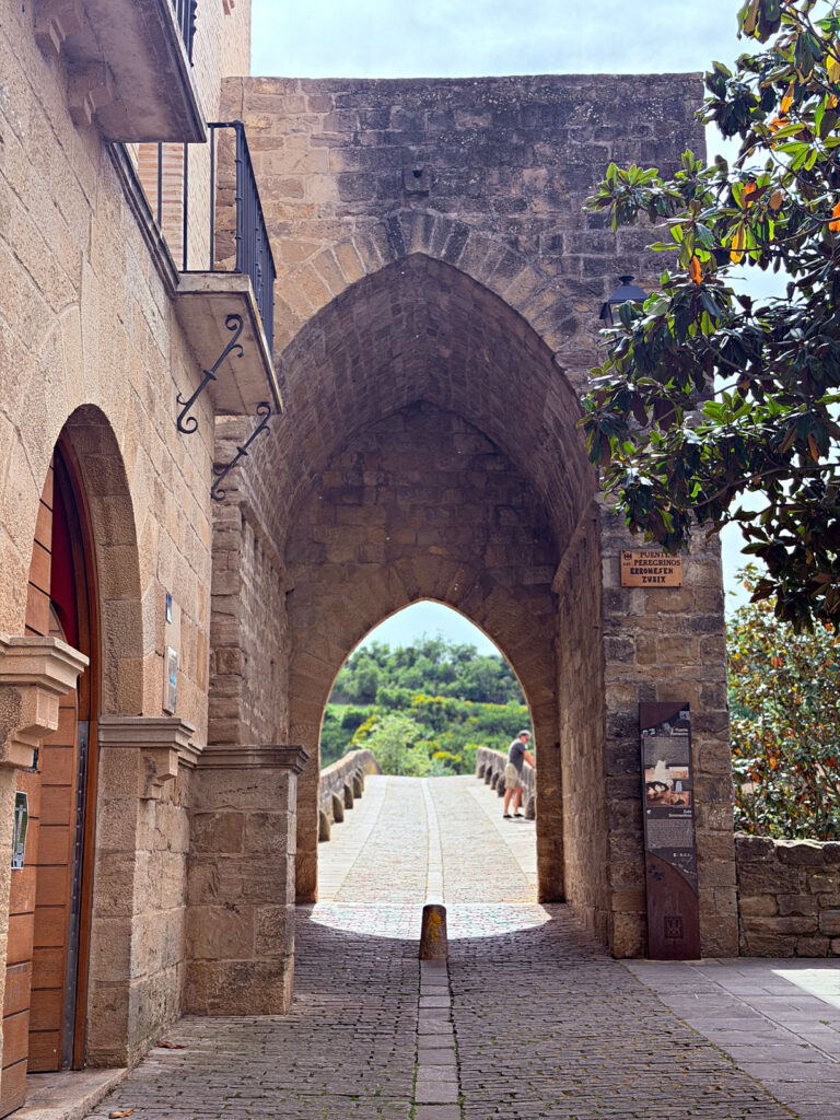 Stone archway leading to the medieval pilgrims’ bridge in Puente la Reina, Spain.
