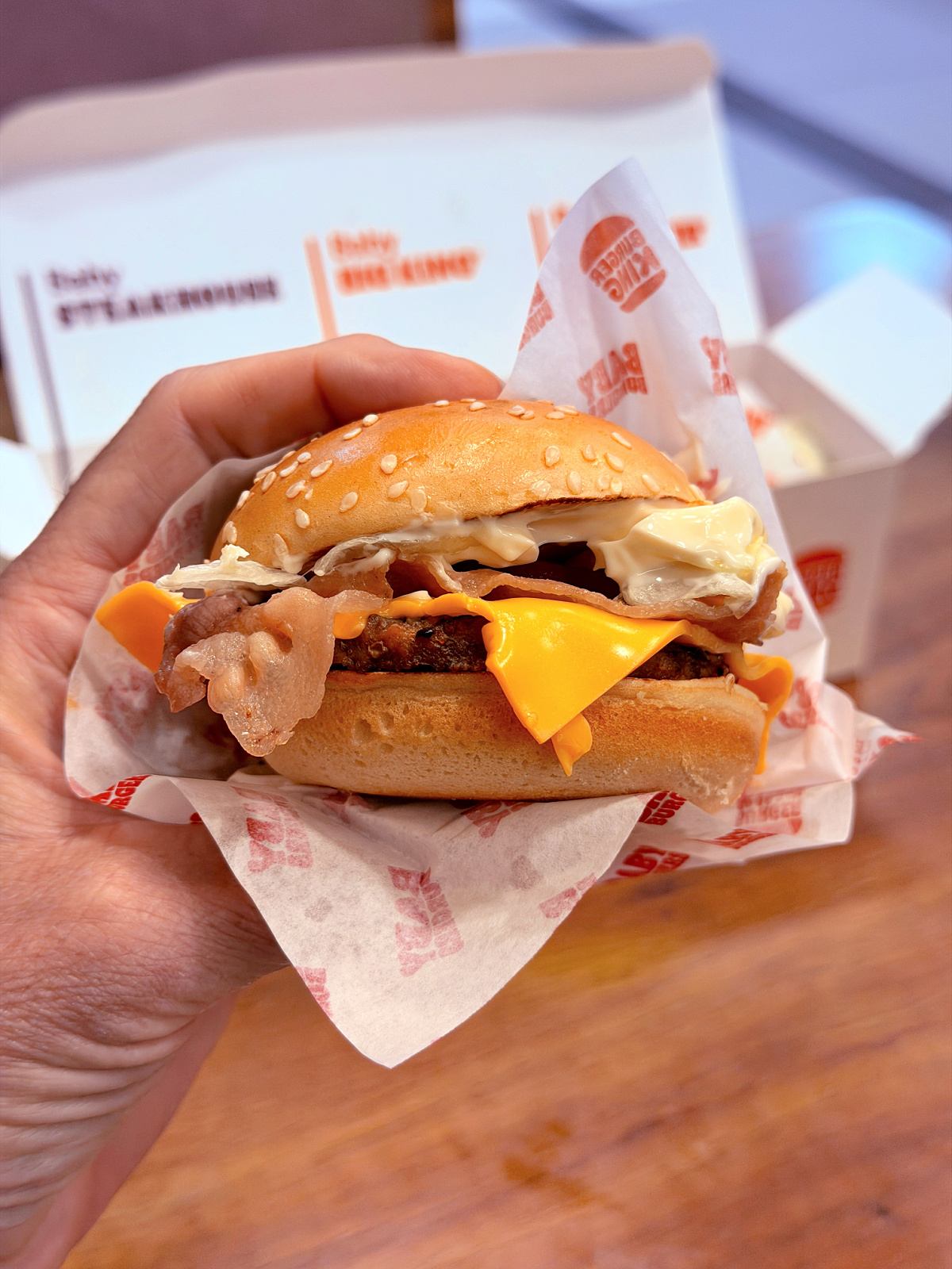 Bacon cheeseburger held in one hand at a Burger King in Pamplona, Spain.