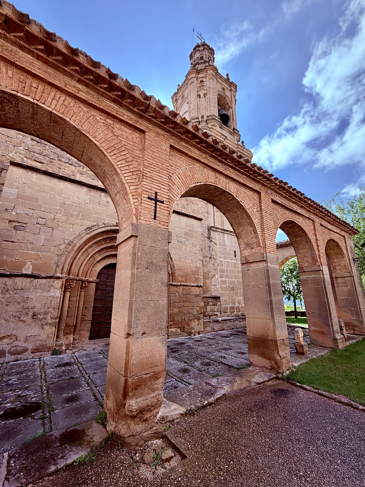 Stone church with an arched portico beneath a bright blue sky along the Camino de Santiago.