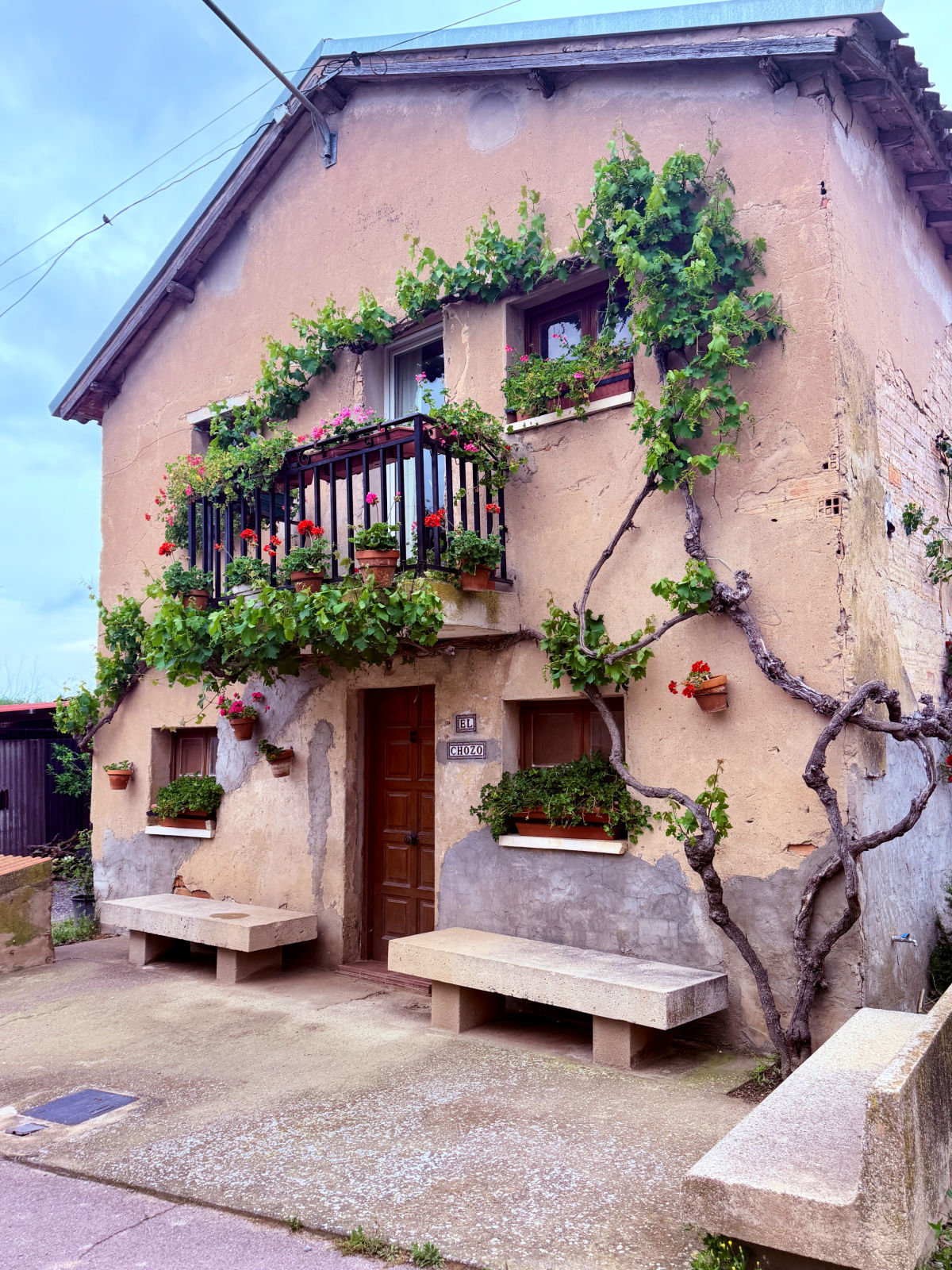 Rustic stone house with wooden balconies and climbing vines in Spain.