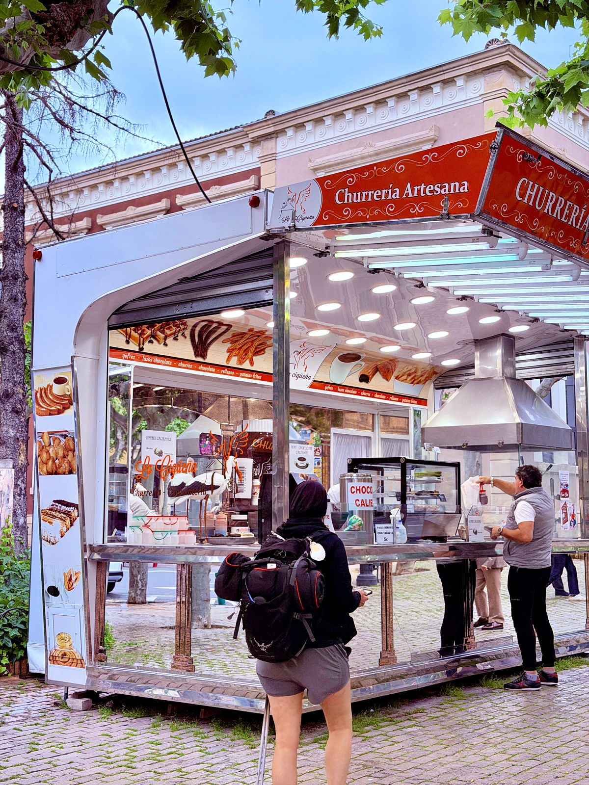 Customers ordering from a brightly lit churrería stand in Logroño, Spain.