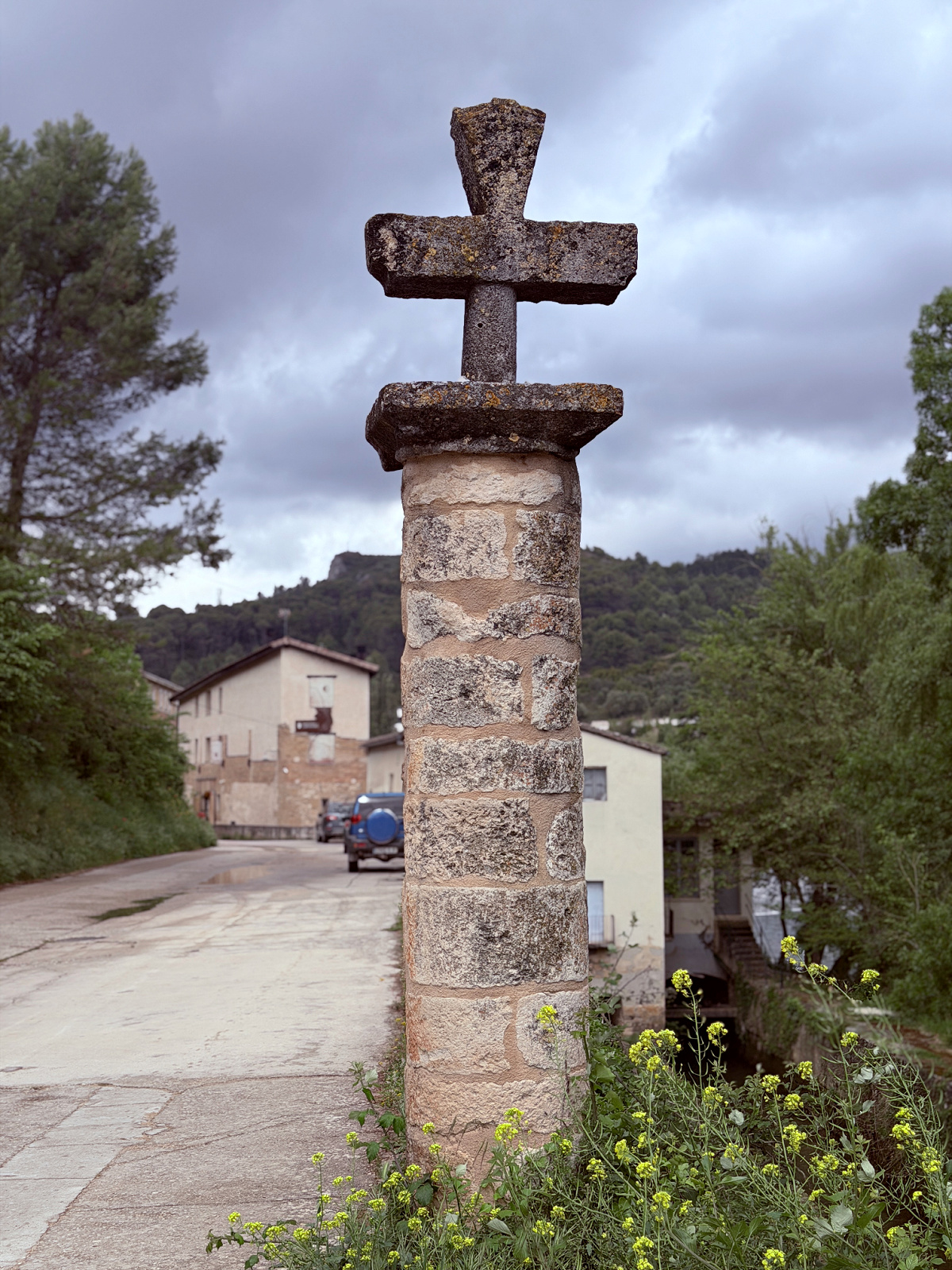 Weathered stone cross standing beside a road along the Camino Francés.