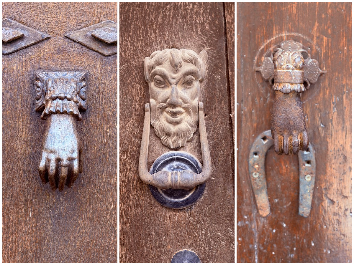 Three antique metal door knockers shaped like hands and a bearded face.