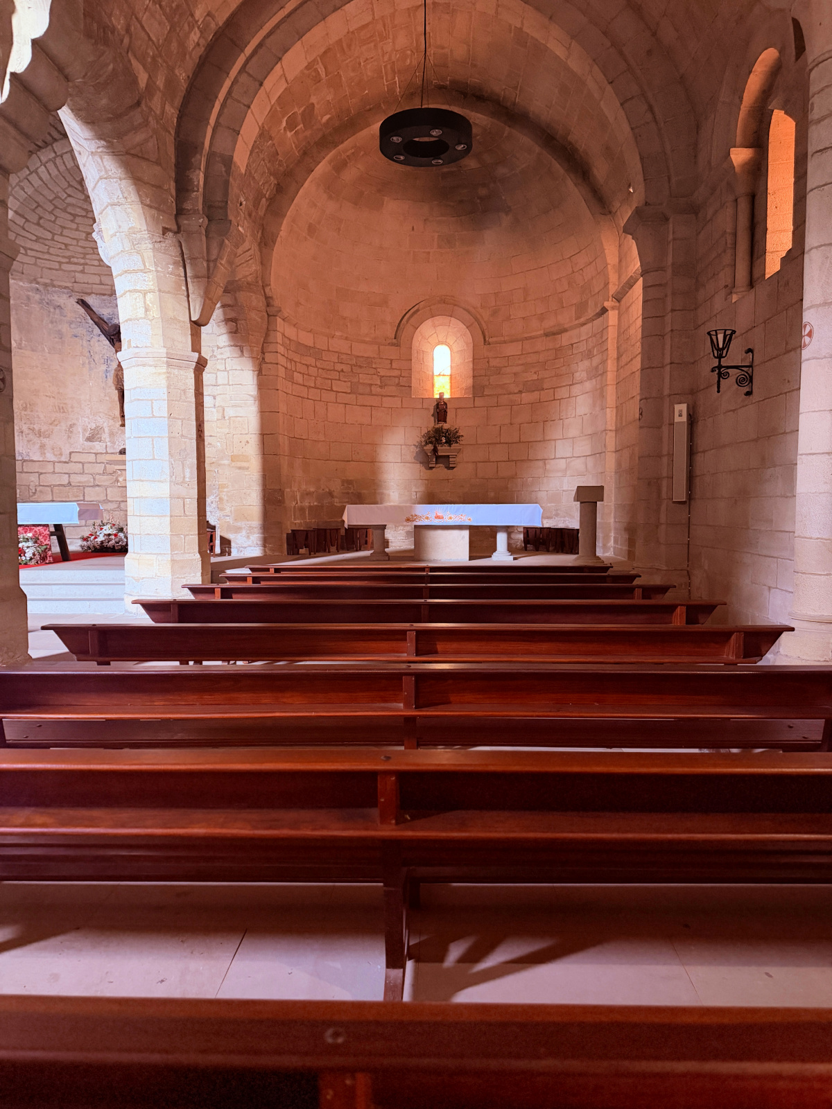 Stone interior, wooden pews, and altar inside Iglesia del Crucifijo in Puente la Reina.