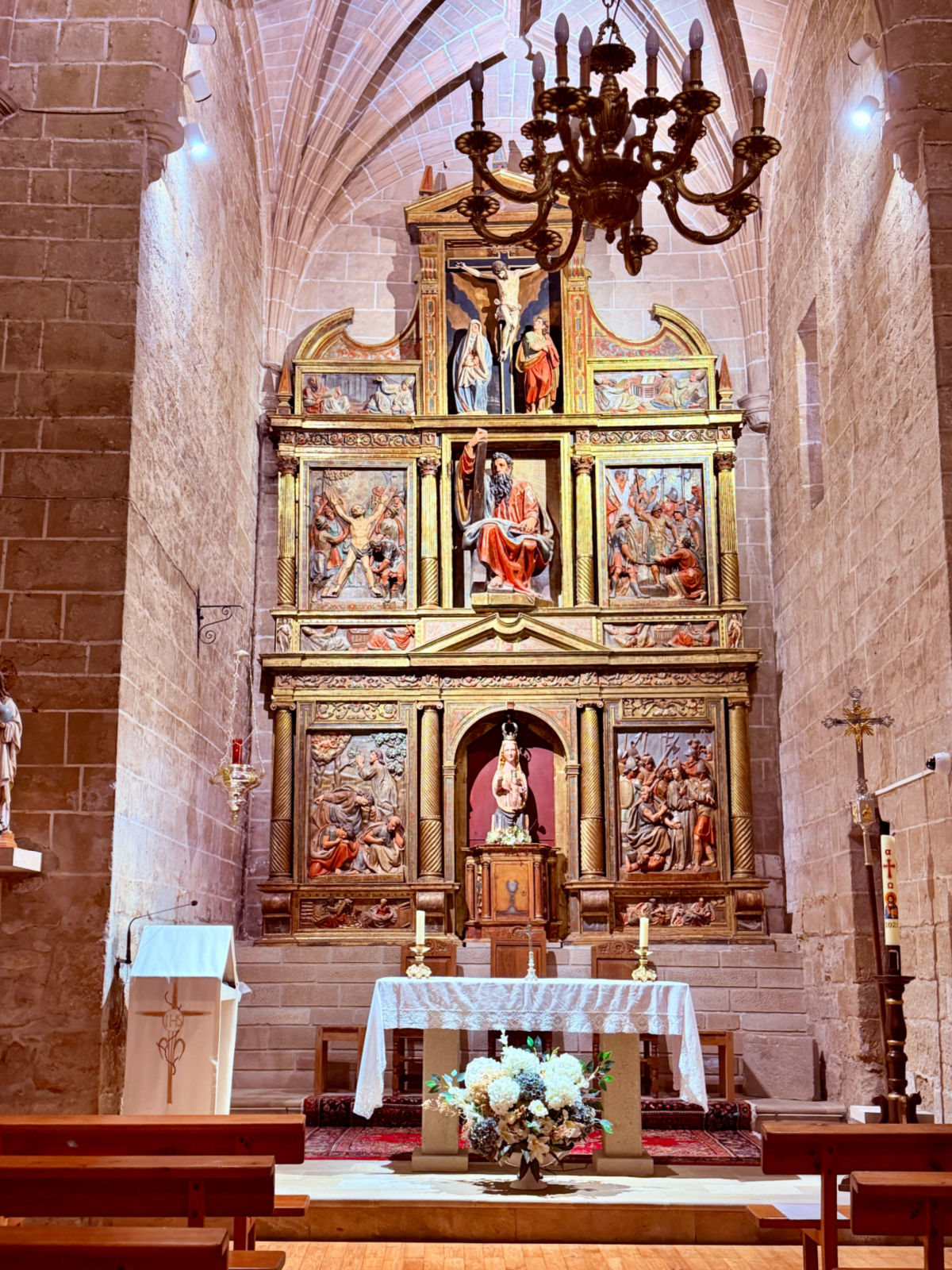 Altar and religious artwork inside a historic stone church in Puente la Reina.