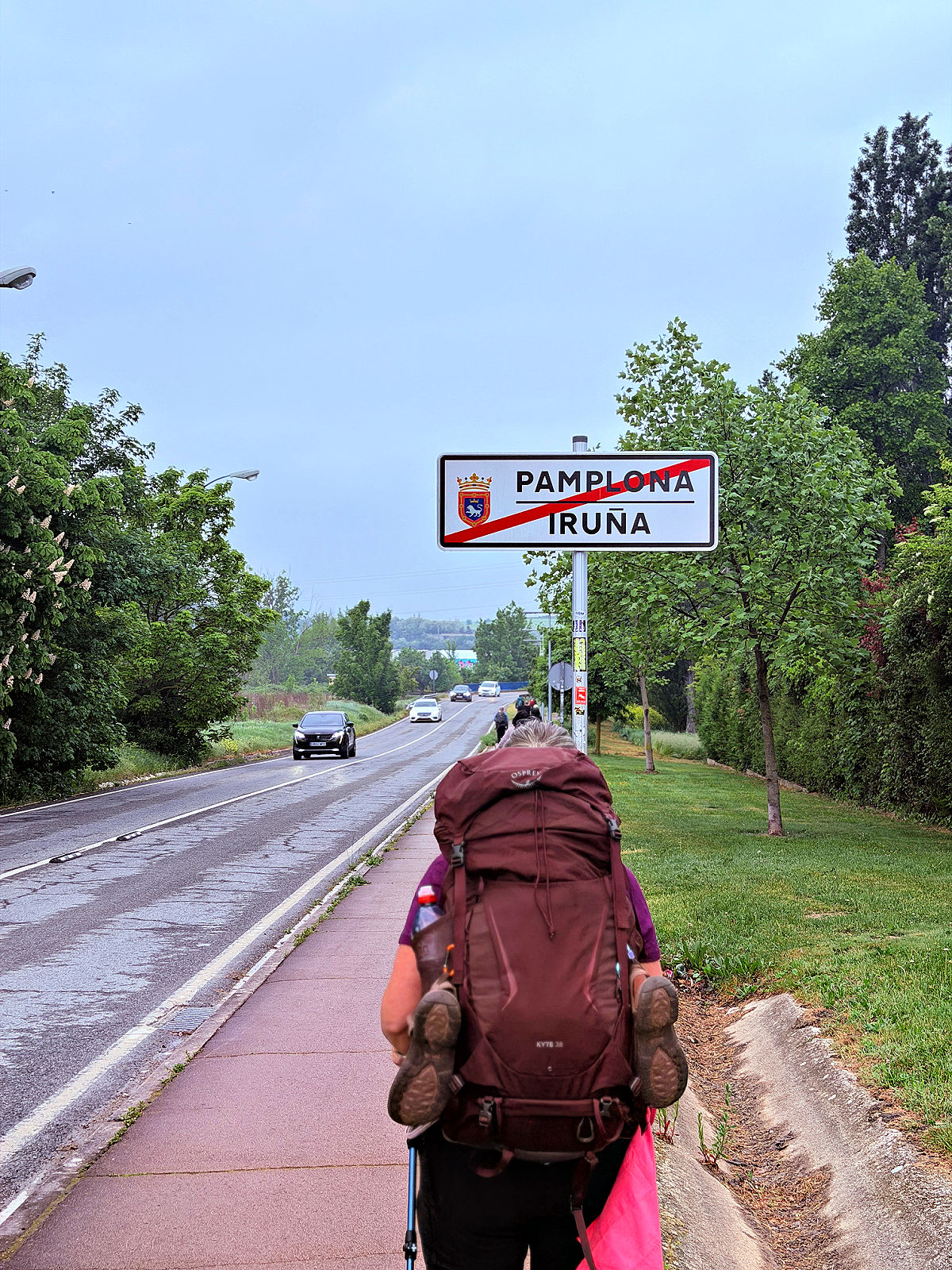 Camino pilgrim walking past the city-limit sign while leaving Pamplona.
