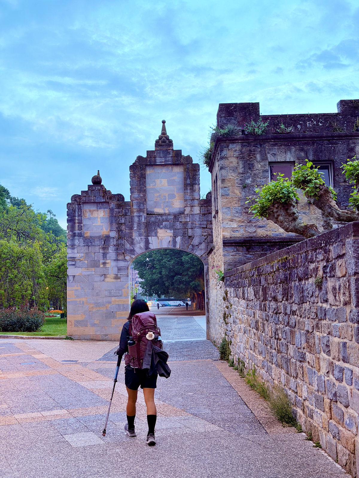 Camino pilgrim walking through a stone gateway while leaving Pamplona.
