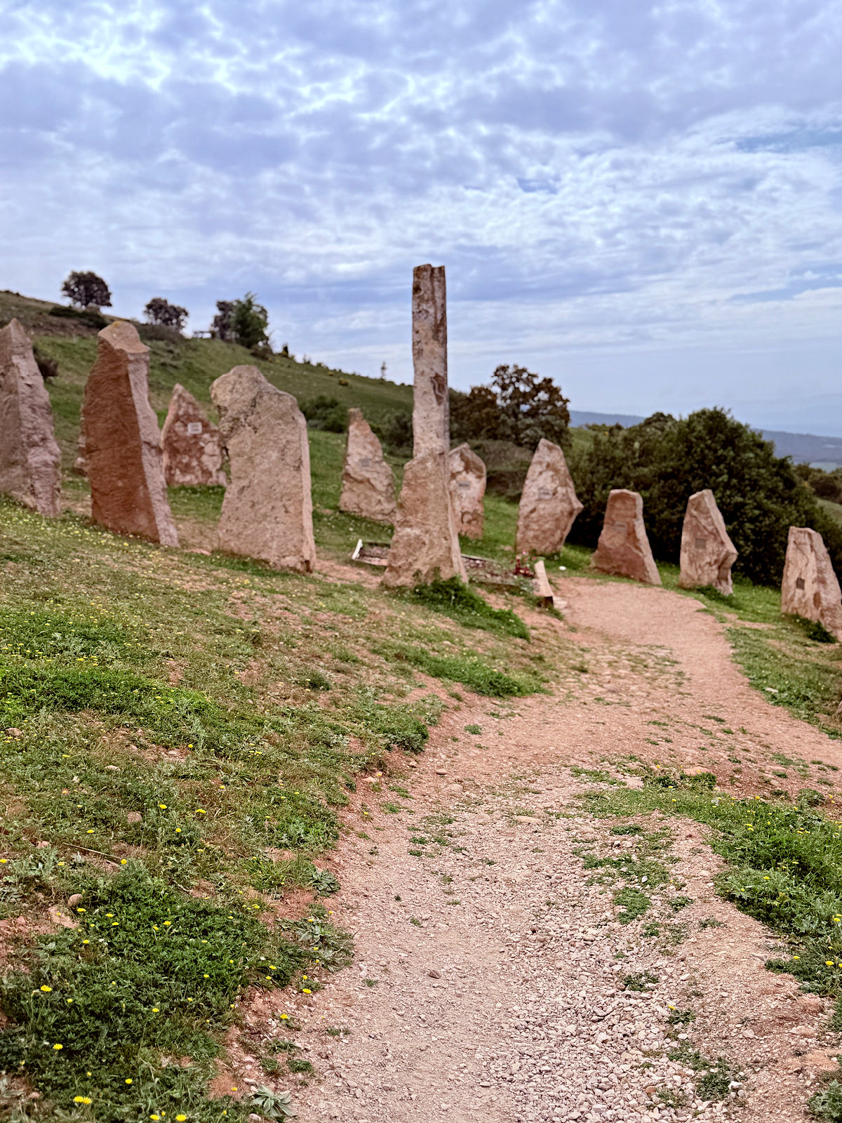 Upright stone memorials lining a gravel path on a hillside near Alto del Perdón.